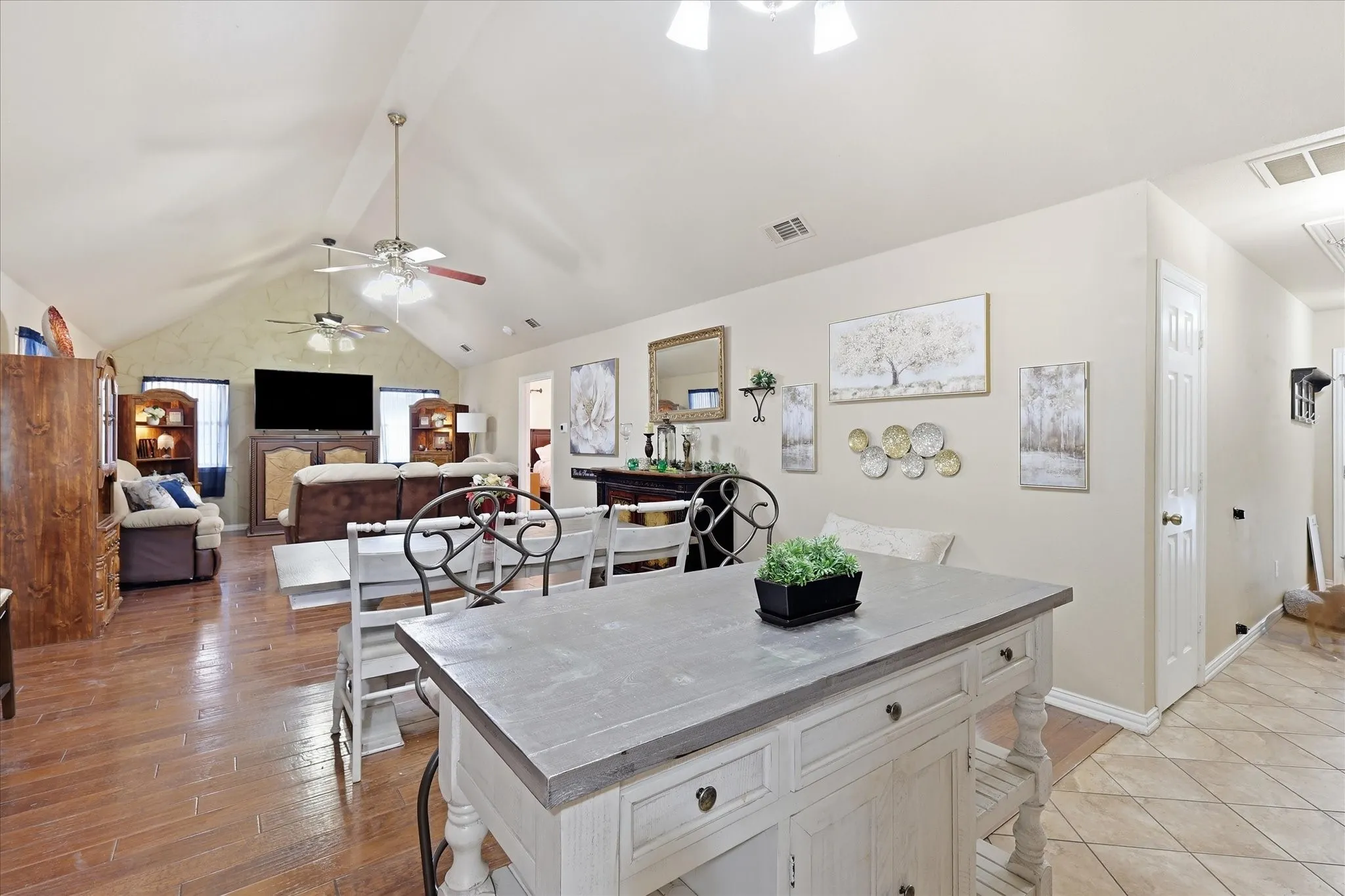 Vaulted ceiling with dual ceiling fans, wood-finish flooring, and a kitchen island with a light-toned countertop