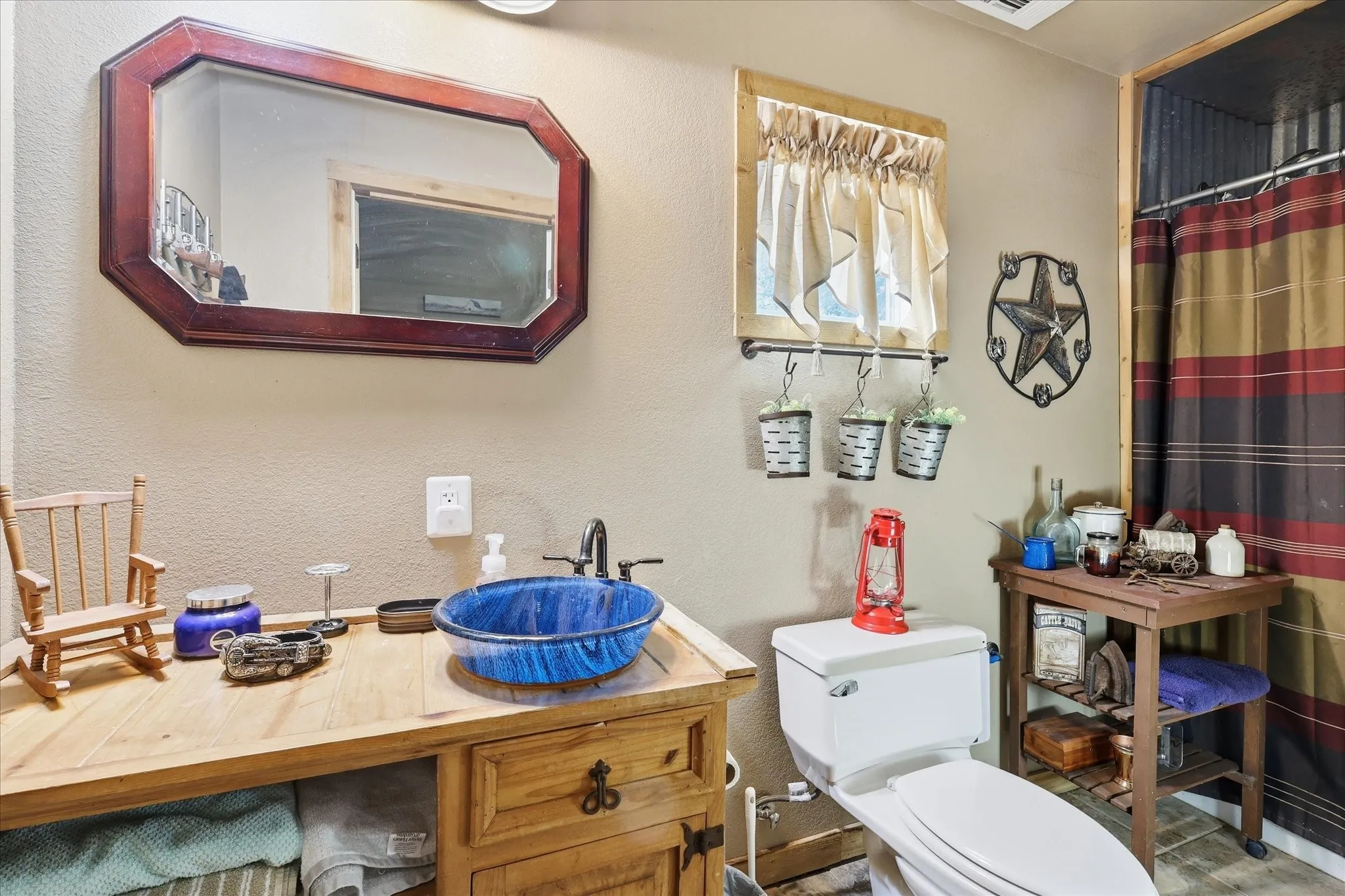Wooden vanity with a blue glass vessel sink and an octagonal mirror