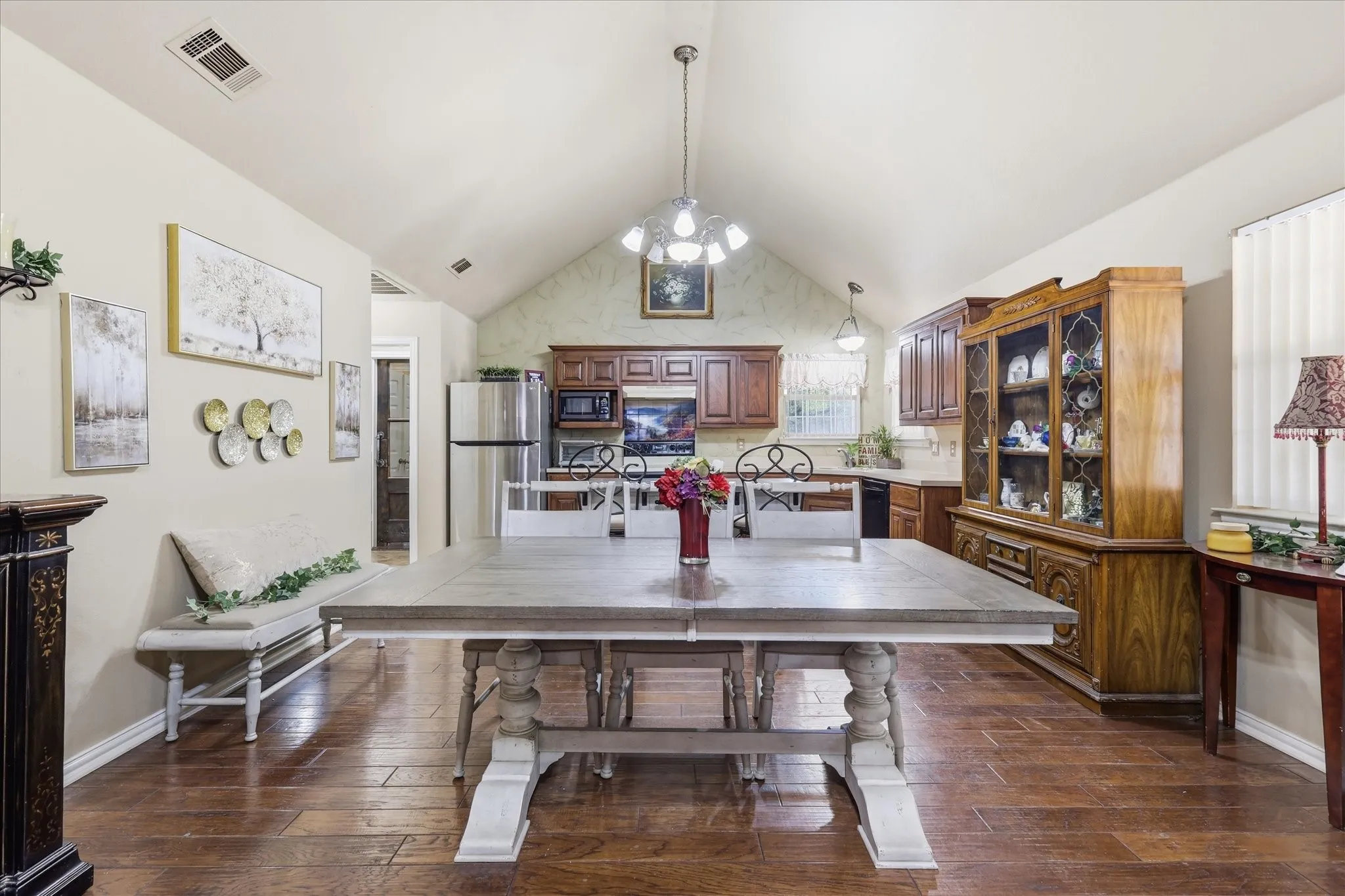 Vaulted ceiling with decorative lighting, wood-finish flooring, and built-in wood cabinetry