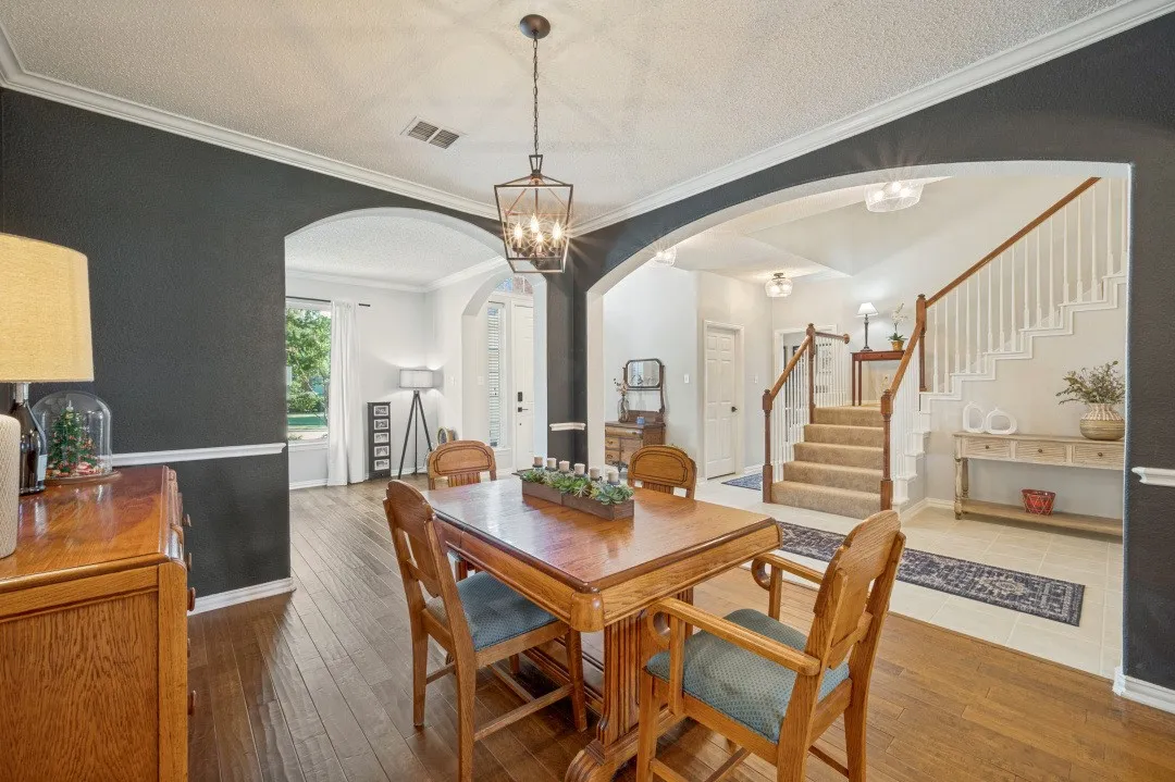 Archways and crown molding accent the interior, featuring wood-finish flooring and a staircase with white balusters