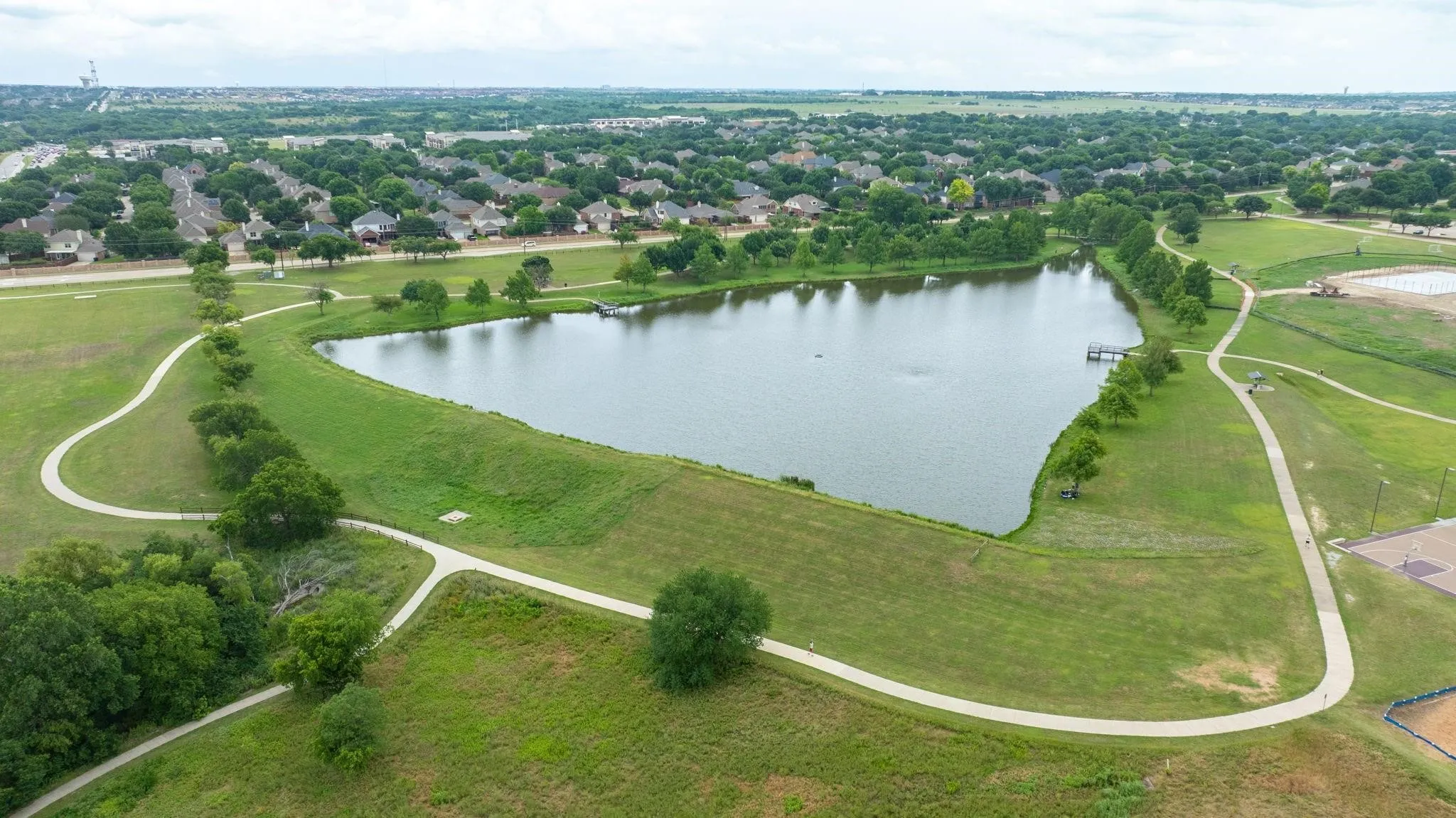 Expansive green spaces featuring a large body of water, paved walking paths, and mature trees