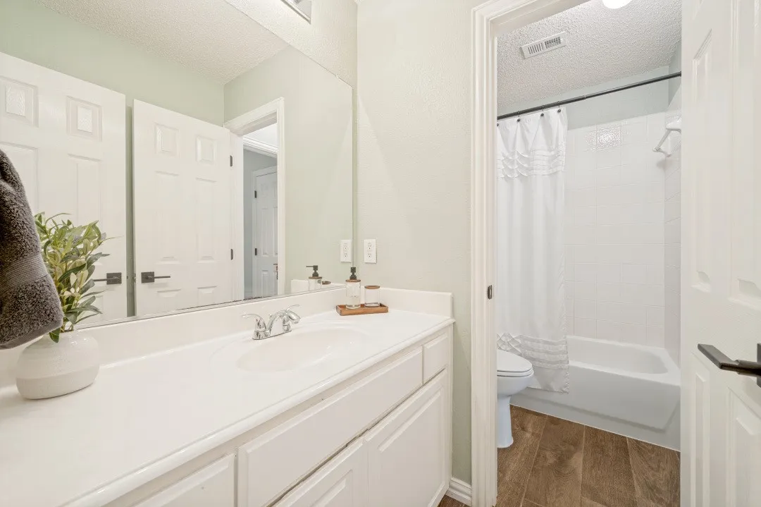 Bathroom featuring a single vanity with an integrated sink, large mirror, and wood-finish flooring