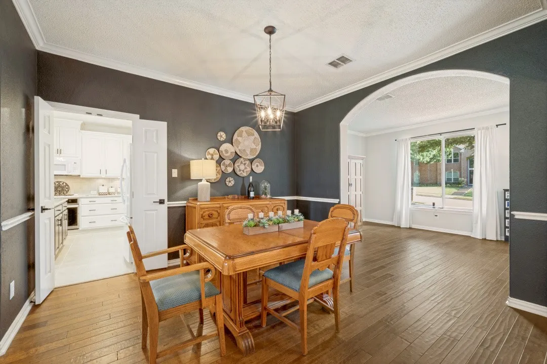Wood-finish flooring, crown molding, double doors, arched doorway, and a large window