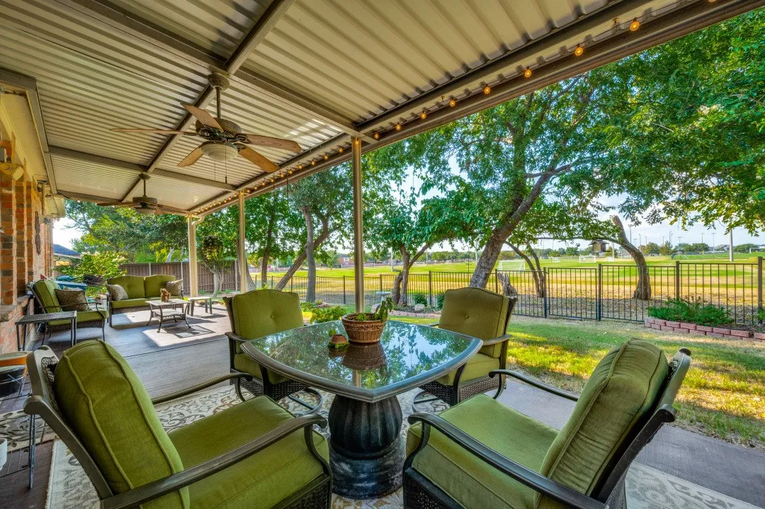Covered patio featuring a corrugated metal roof, two ceiling fans, and string lighting