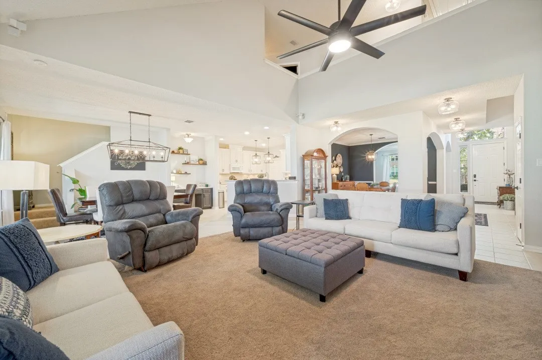 Vaulted ceiling with a contemporary ceiling fan, arched doorways, a built-in staircase, and varied overhead lighting fixtures