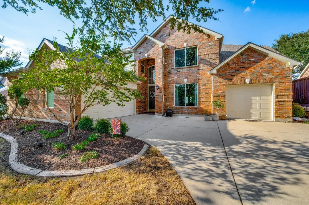 Brick exterior with multiple windows, arched entryway, and two attached garage doors