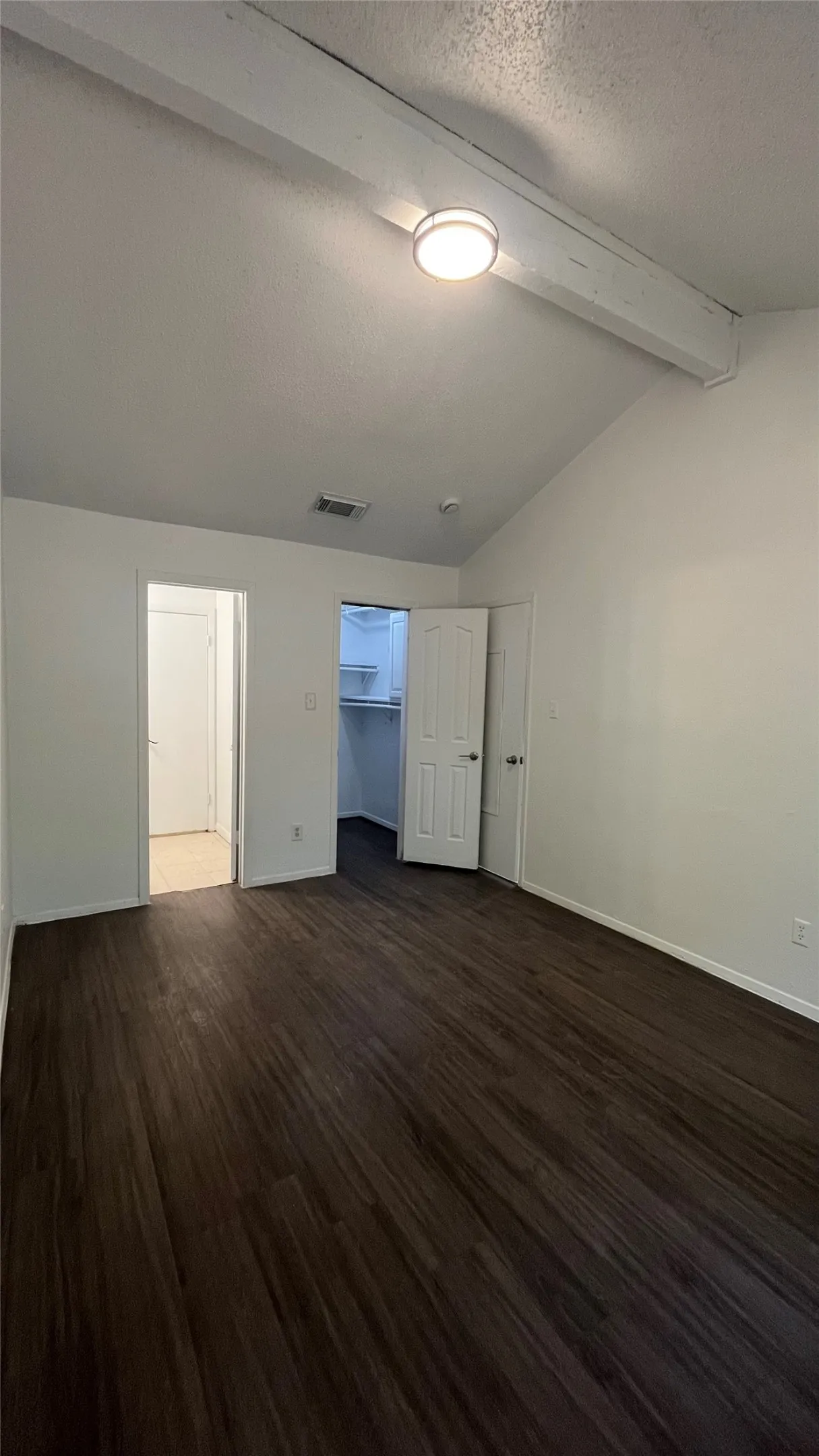 Bedroom 1 -Vaulted ceiling with exposed beam, wood-finish flooring, and a single window