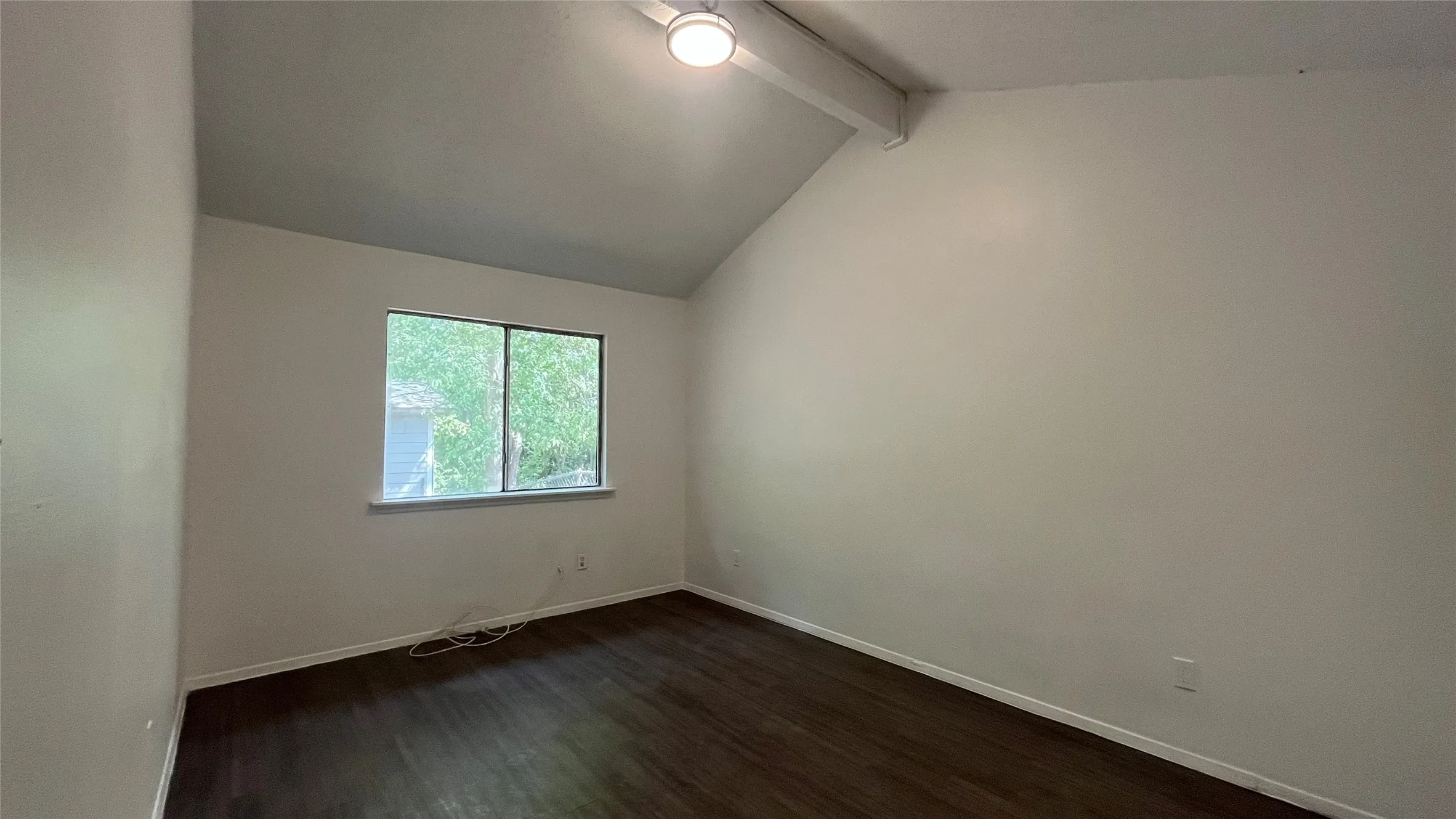 Bedroom 1 -Vaulted ceiling with exposed beam, wood-finish flooring, and a single window