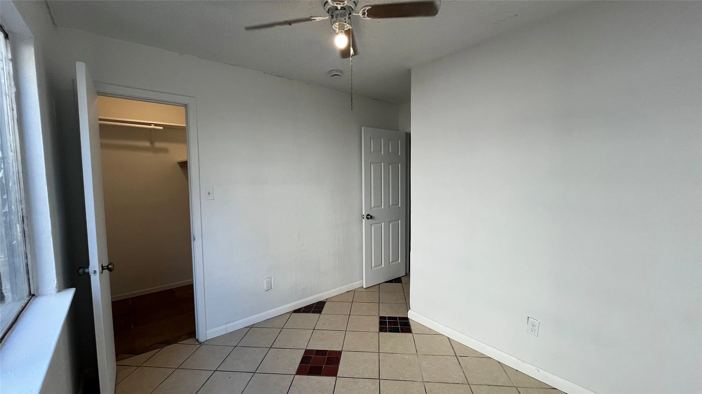 Bedroom 3 - Tile flooring with accent inserts, ceiling fan with integrated lighting, window with white trim, and a white interior door
