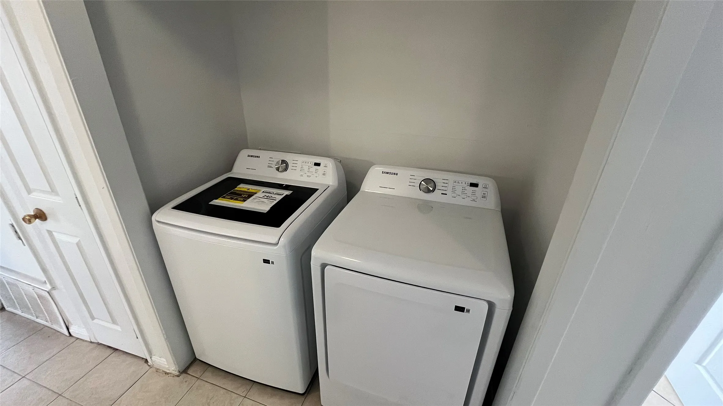 Full-size brand new Samsung laundry appliances within a dedicated alcove