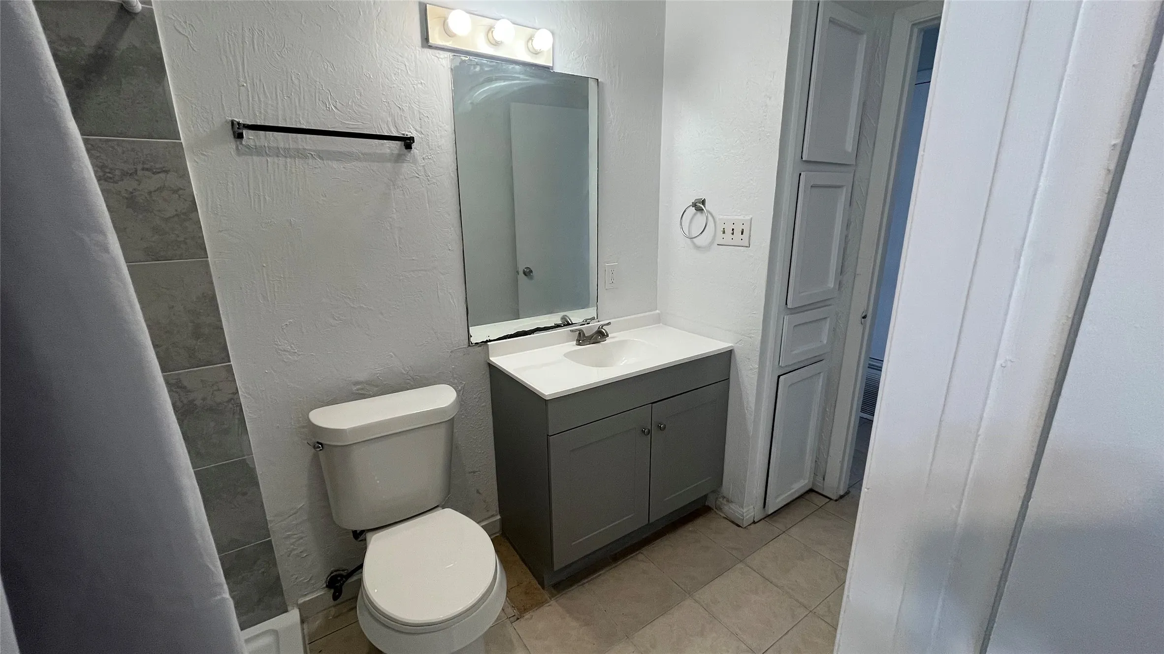Bathroom 1 featuring a vanity with a white countertop, modern gray cabinetry, a built-in storage cabinet, and tiled flooring