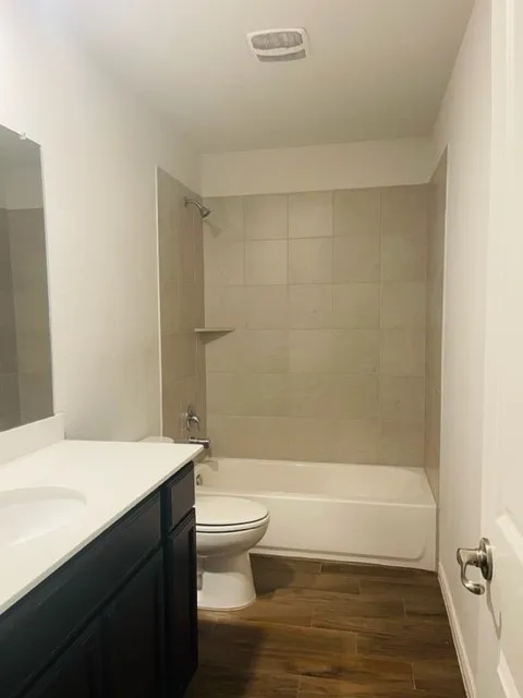 Bathroom featuring a single vanity with an integrated sink, a white countertop, and dark cabinetry