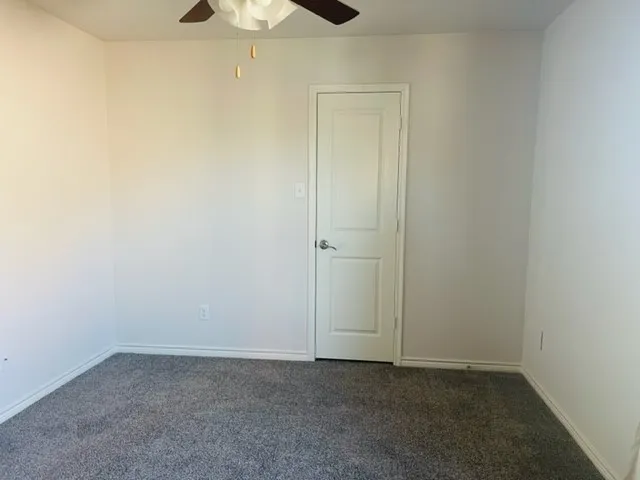 Neutral wall finishes, textured carpeting, and a ceiling fan with integrated lighting