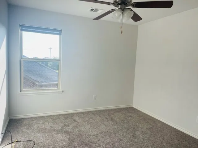 Neutral wall color, gray carpet, single window, and a ceiling fan with integrated lighting