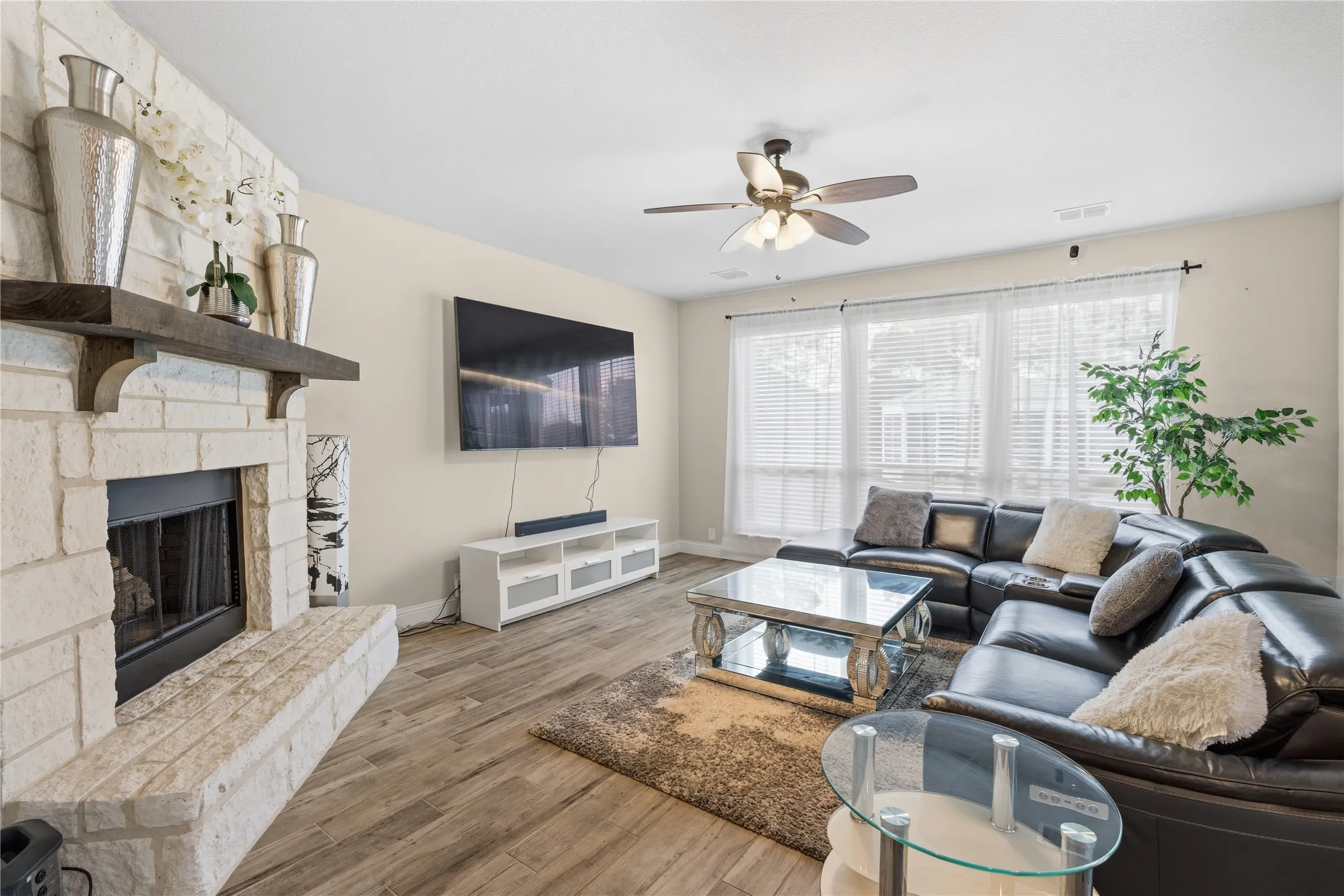 Living room featuring light wood-style floors, ceiling fan, and a fireplace