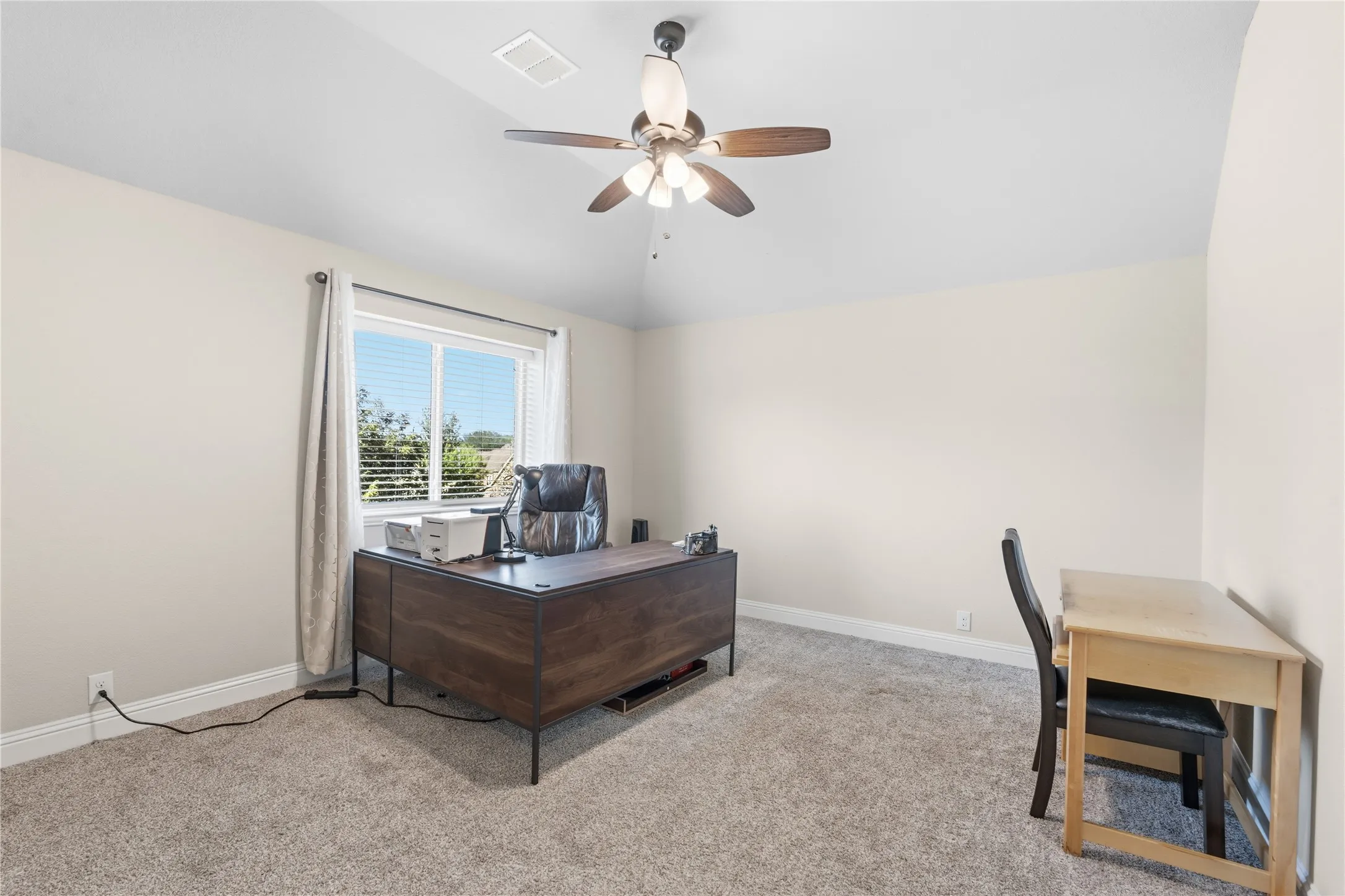 Home office featuring light carpet, a ceiling fan, and vaulted ceiling