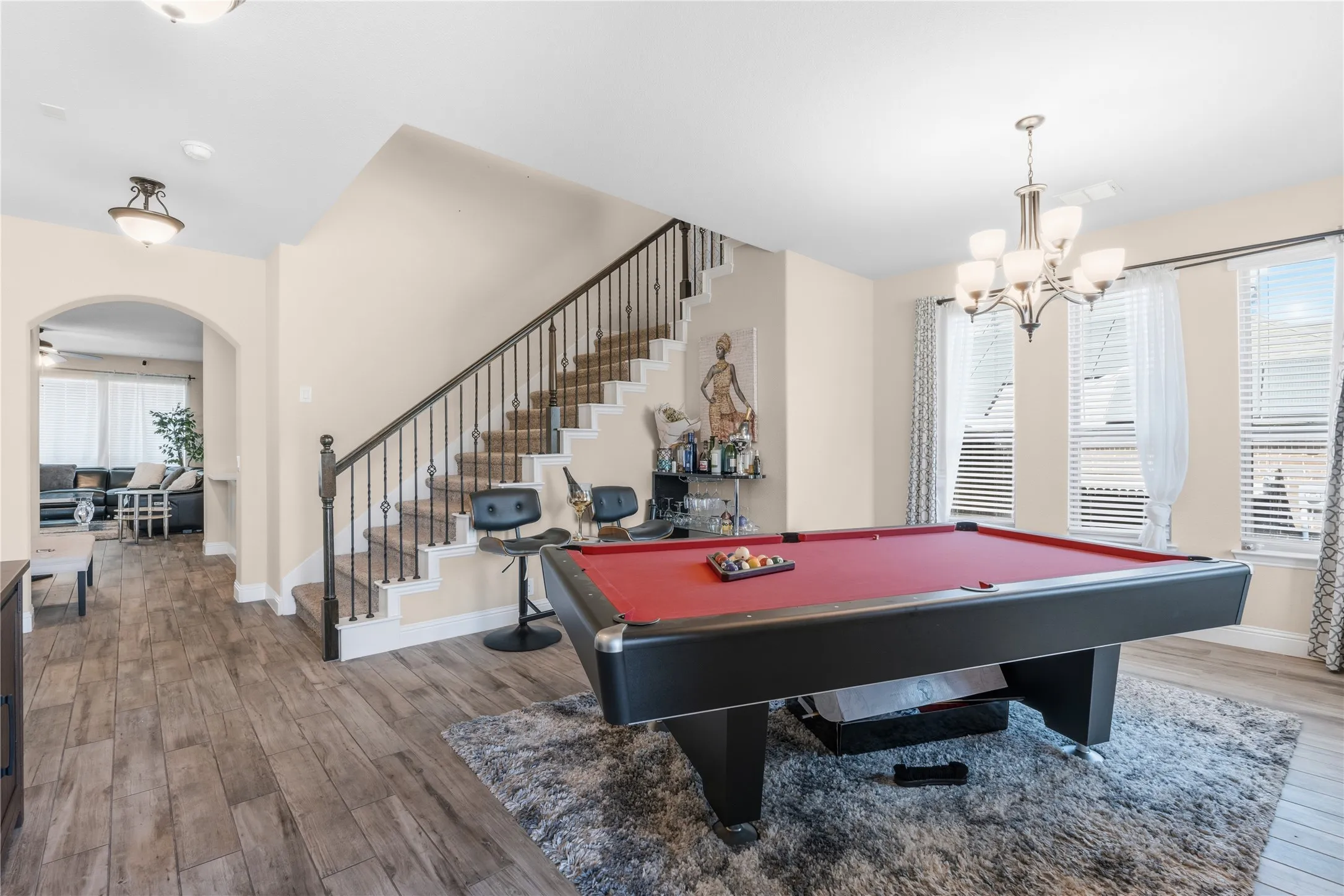 Game room featuring wood finished floors, pool table, arched walkways, and suspended lighting