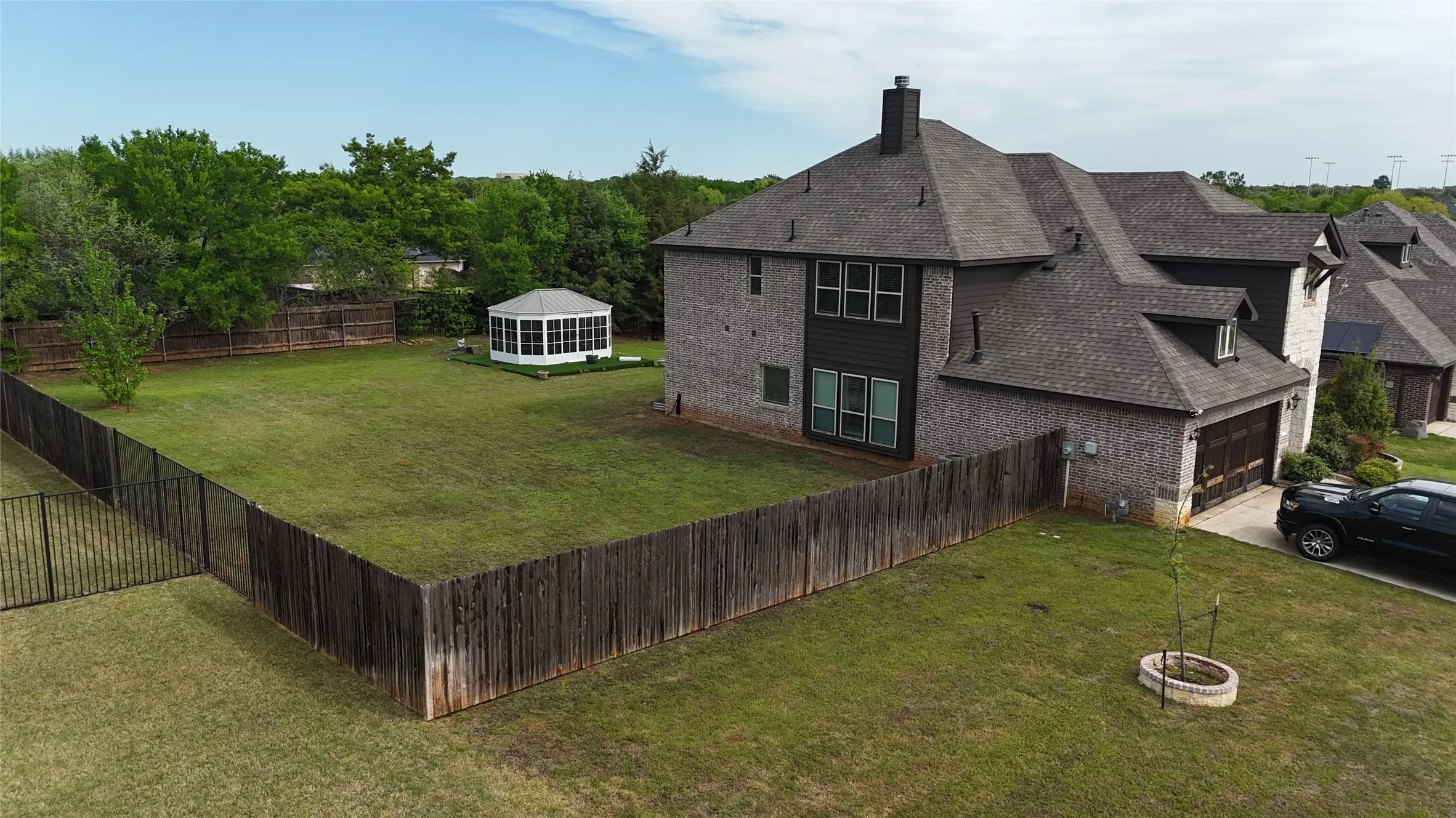 View of side of home with a fenced backyard, brick siding, a chimney, and driveway
