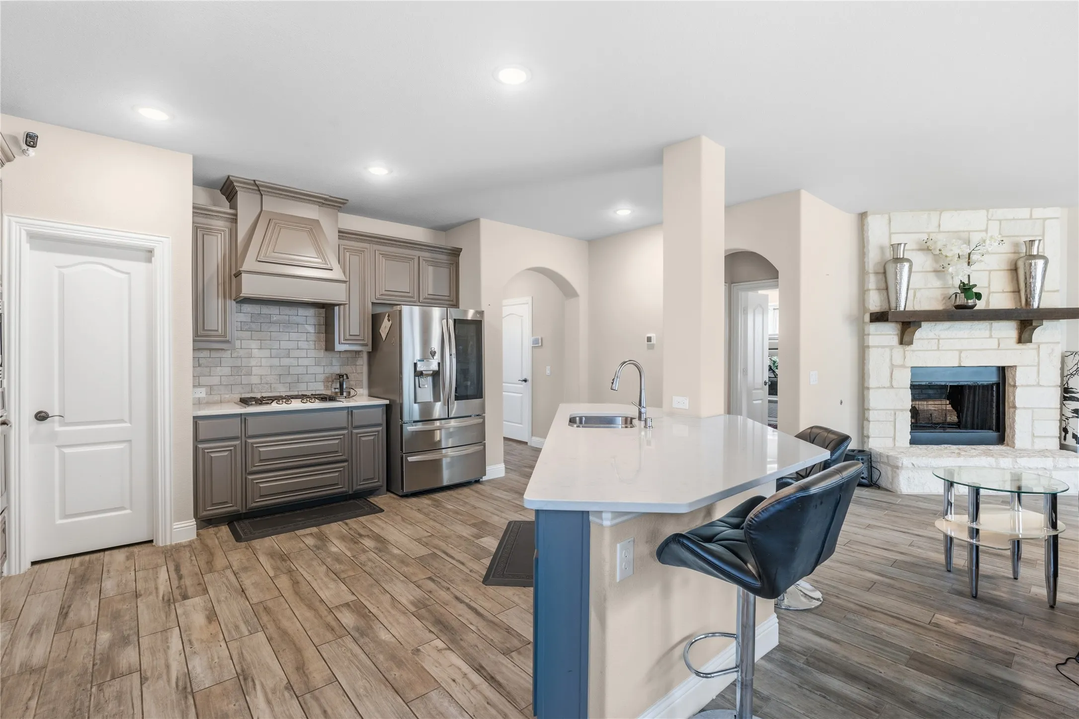 Kitchen with open floor plan, a fireplace, stainless steel appliances, light wood-style flooring, and recessed lighting