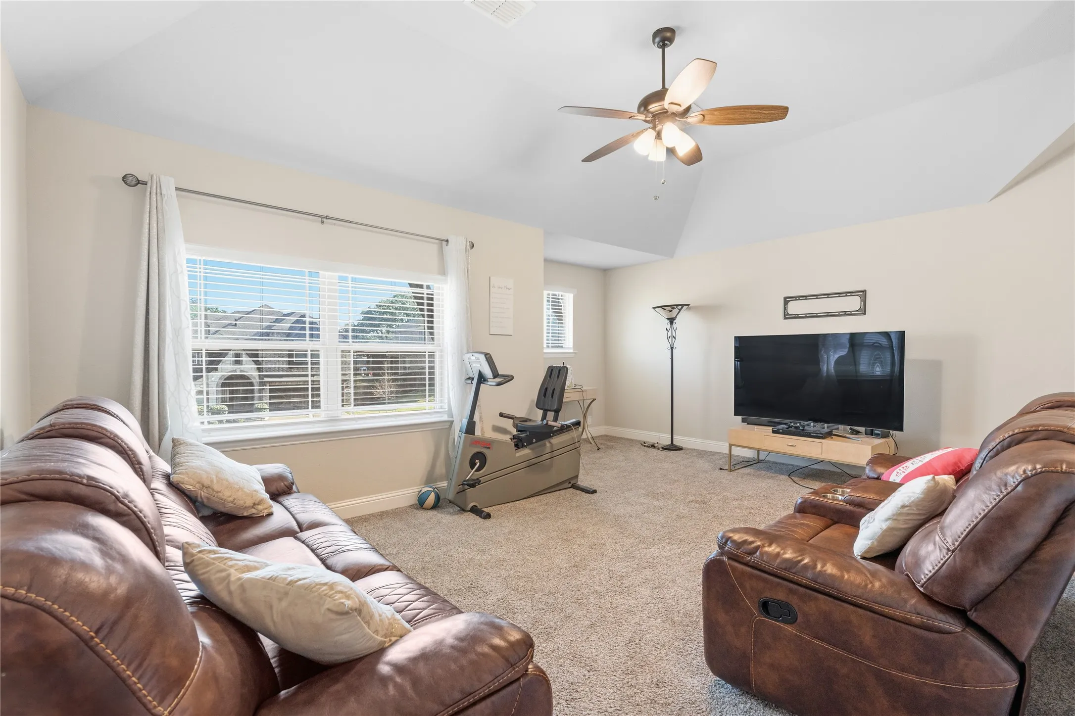 Living area featuring vaulted ceiling, carpet, and ceiling fan