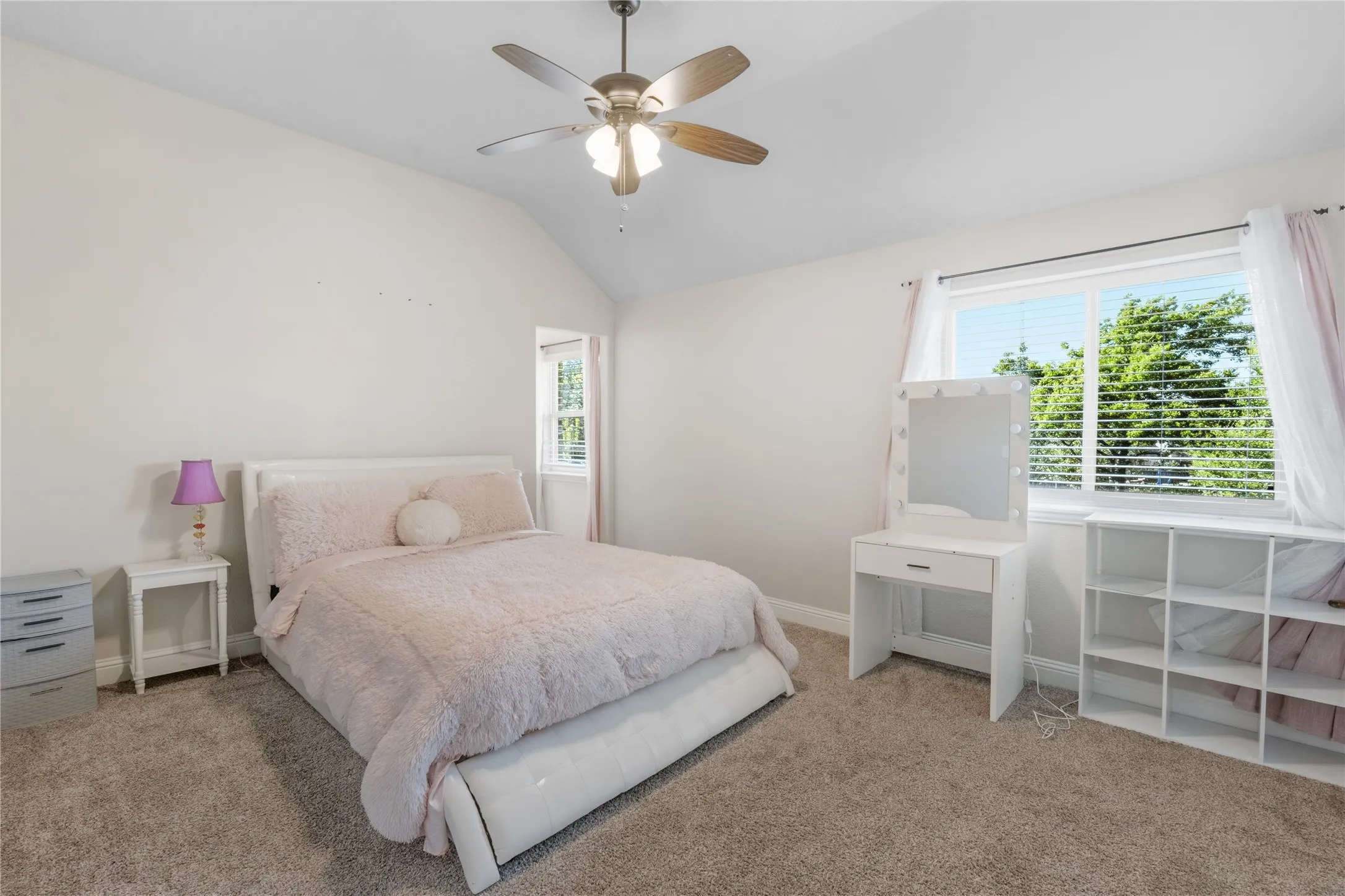Bedroom with lofted ceiling, multiple windows, ceiling fan, and light carpet