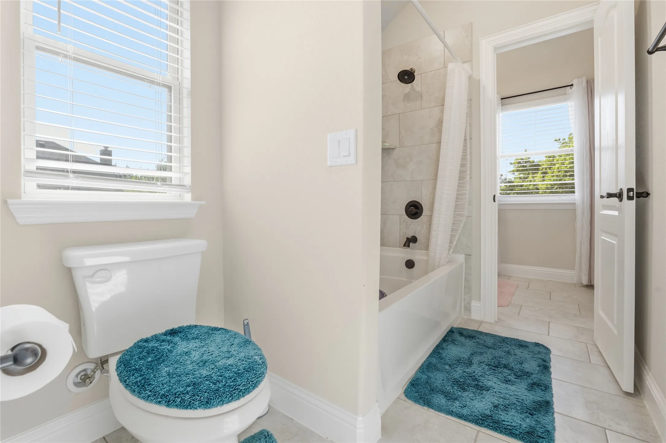 Full bathroom featuring shower / bathtub combination with curtain and light tile patterned floors