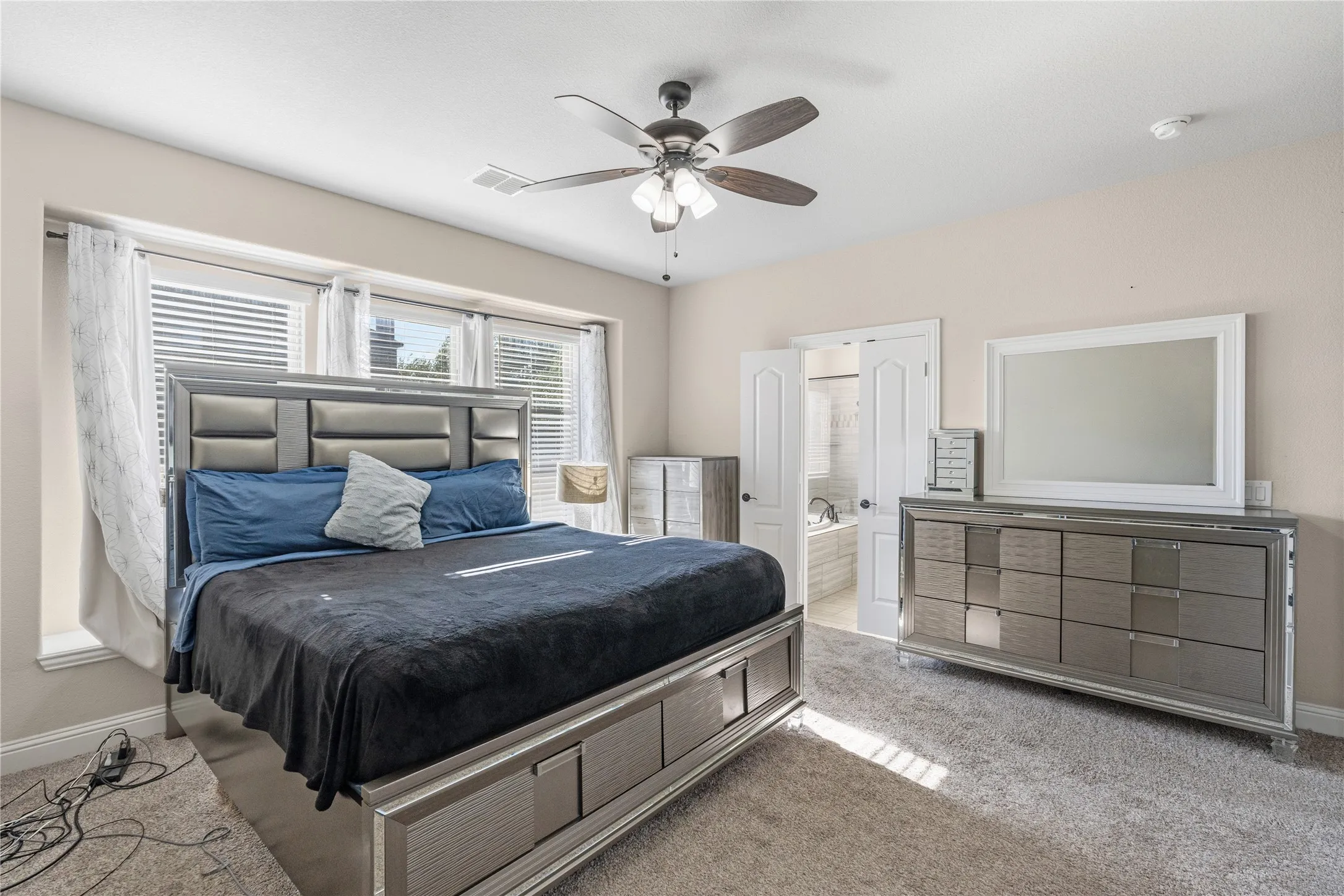Carpeted bedroom featuring ceiling fan and ensuite bathroom