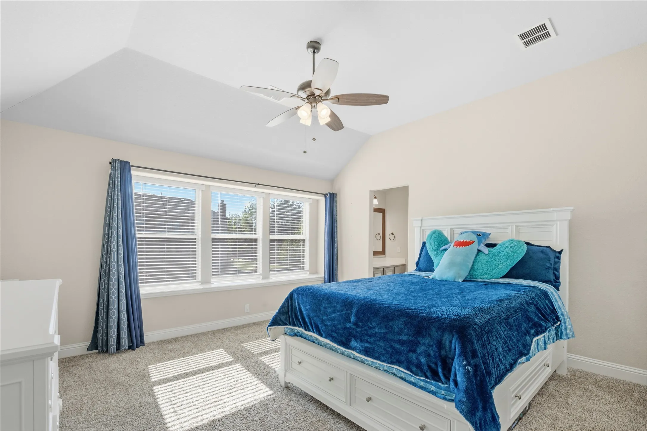 Bedroom featuring vaulted ceiling, light carpet, and a ceiling fan