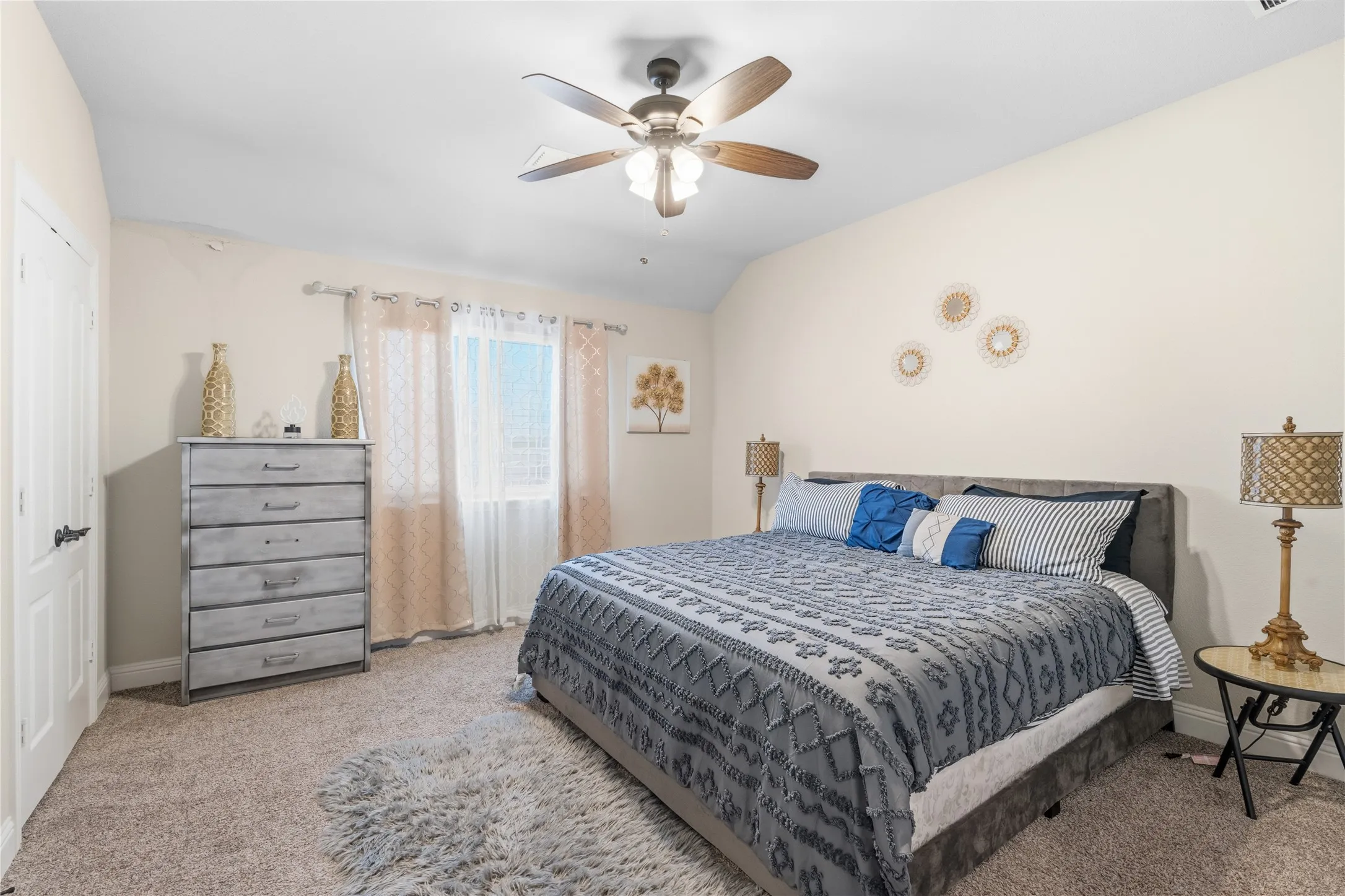 Bedroom with vaulted ceiling, light colored carpet, and ceiling fan