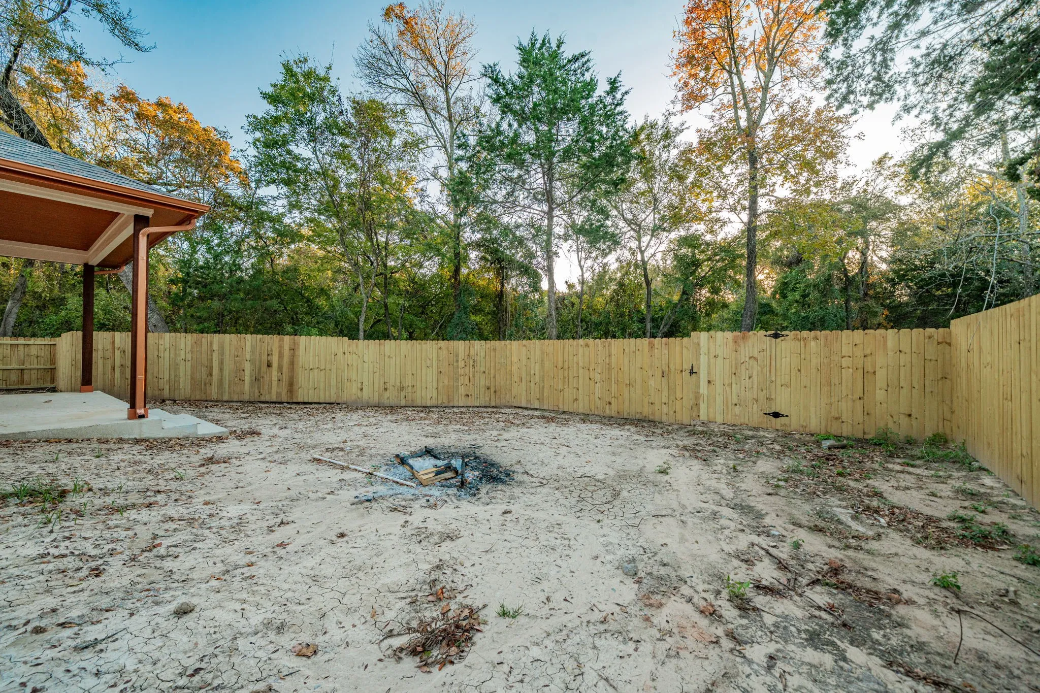 Expansive outdoor space featuring a newly installed privacy fence, concrete patio, and covered porch structure