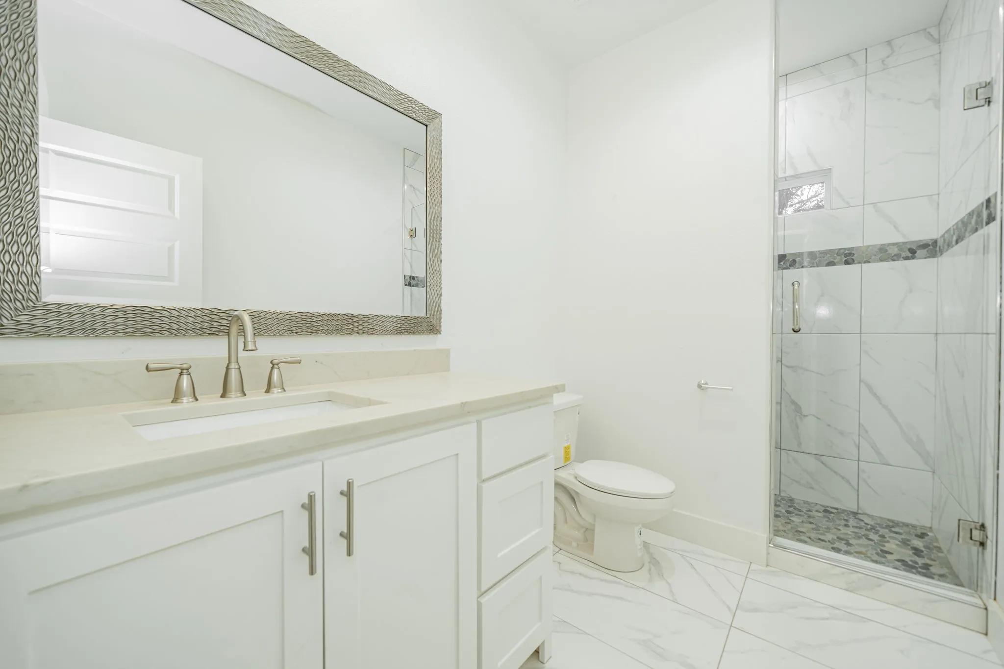 White vanity with brushed nickel hardware, light-toned countertop, and undermount sink