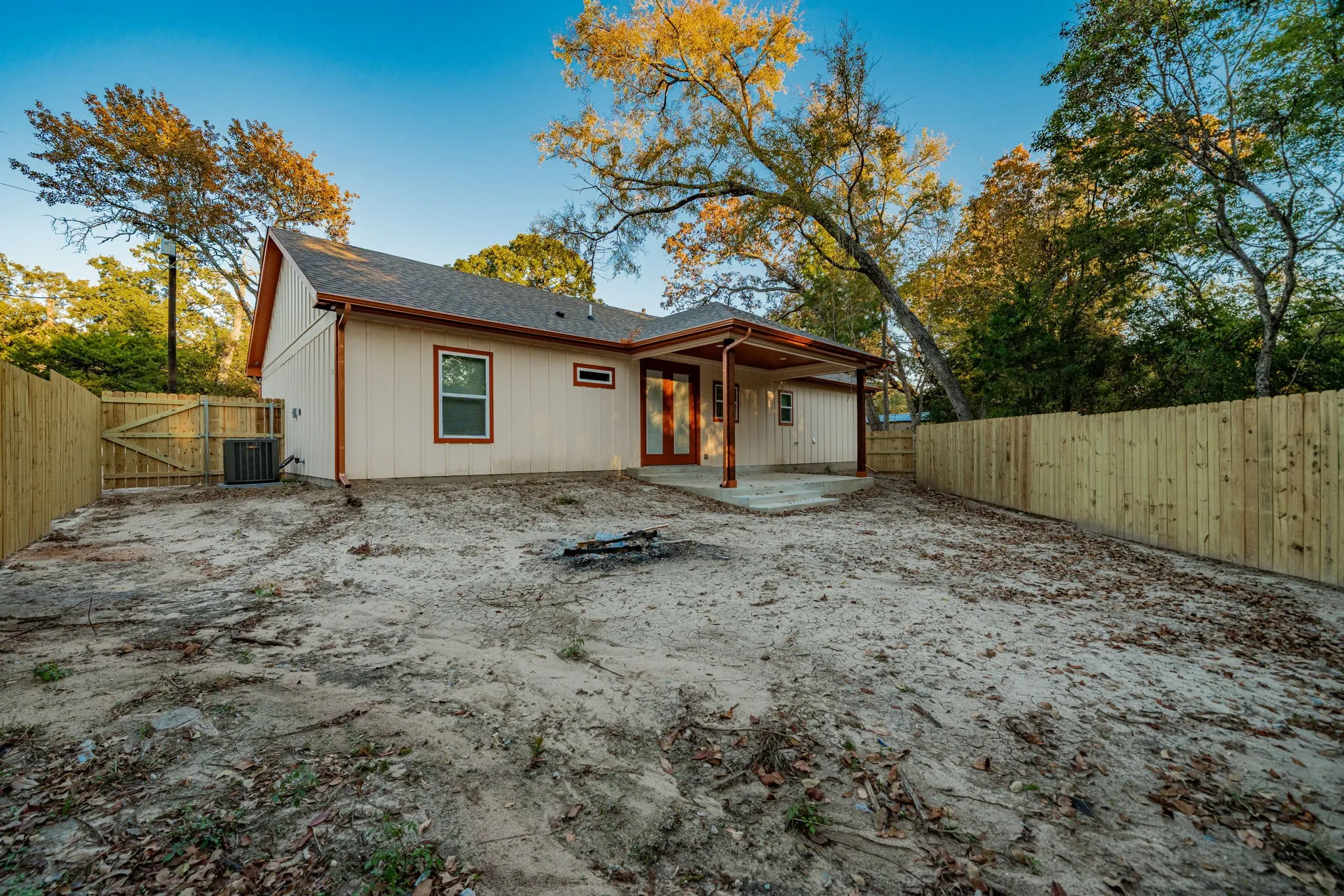 Rear exterior with a covered concrete patio, wood privacy fencing, and an A-frame roofline