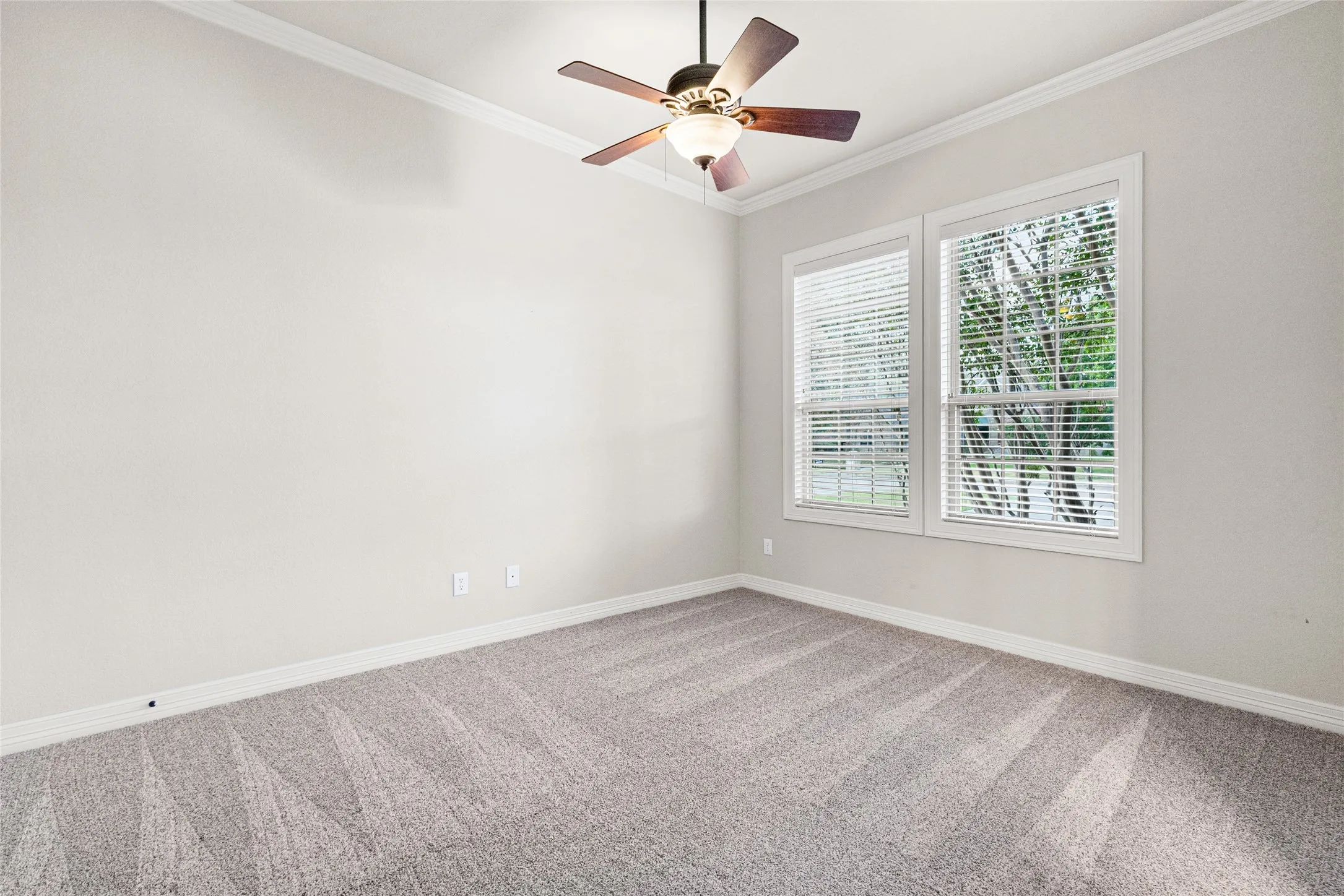 Light-toned carpeting, crown molding, and a ceiling fan with integrated lighting