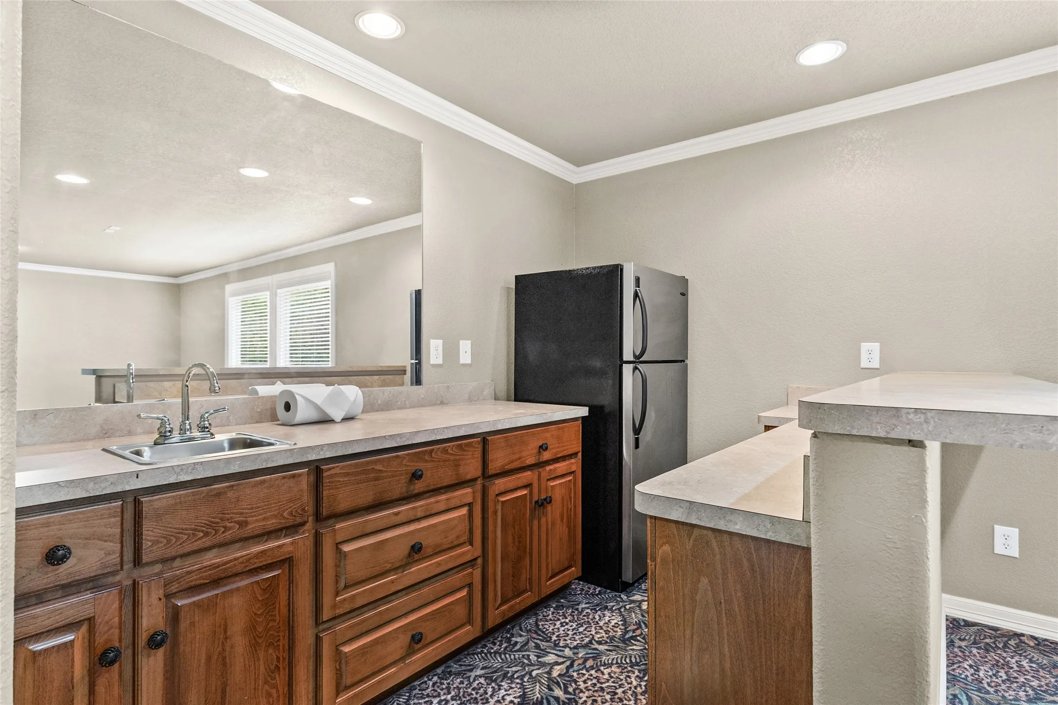 Built-in cabinetry with a stainless steel sink, a refrigerator, light-toned countertops, and recessed lighting