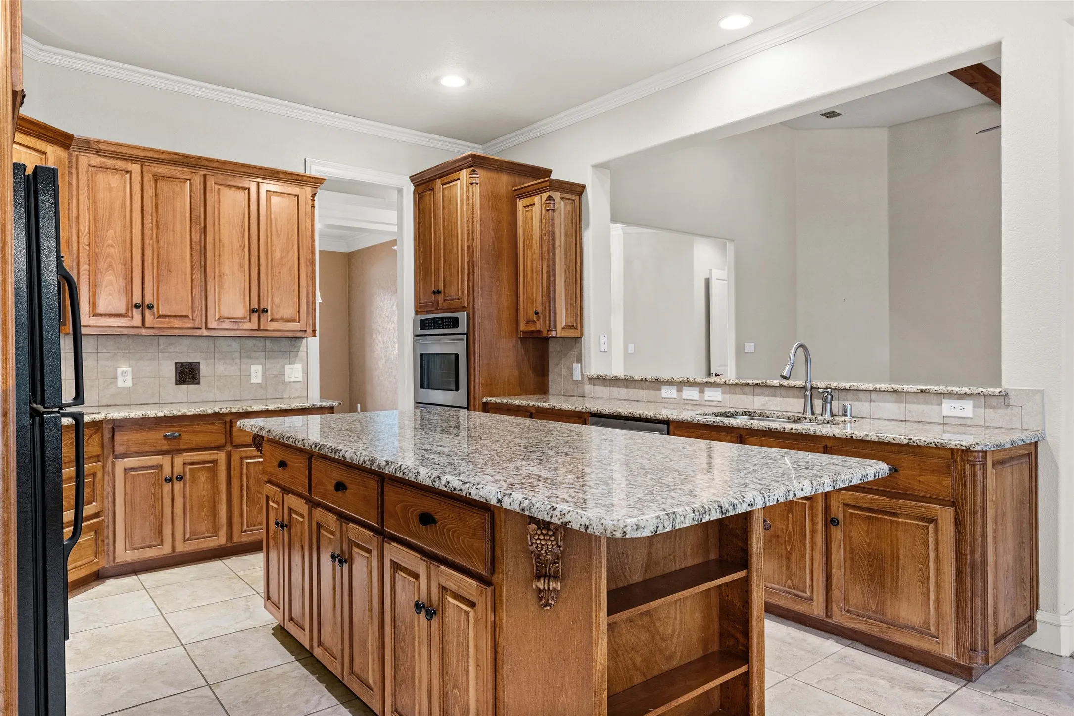 Kitchen featuring wood cabinetry, light-toned tile flooring, recessed lighting, and stone countertops