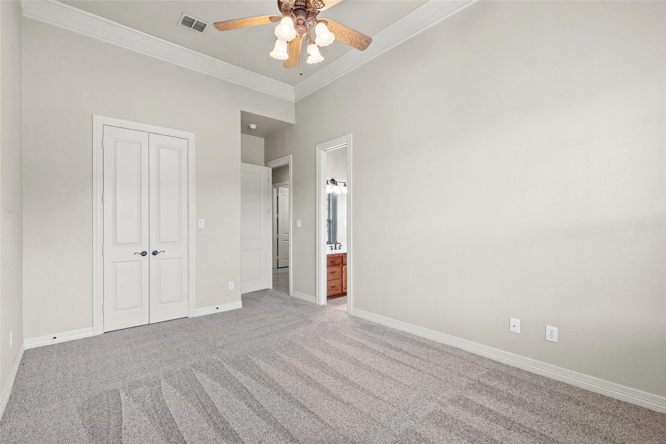 Neutral carpet flooring, crown molding, and a ceiling fan with integrated lighting