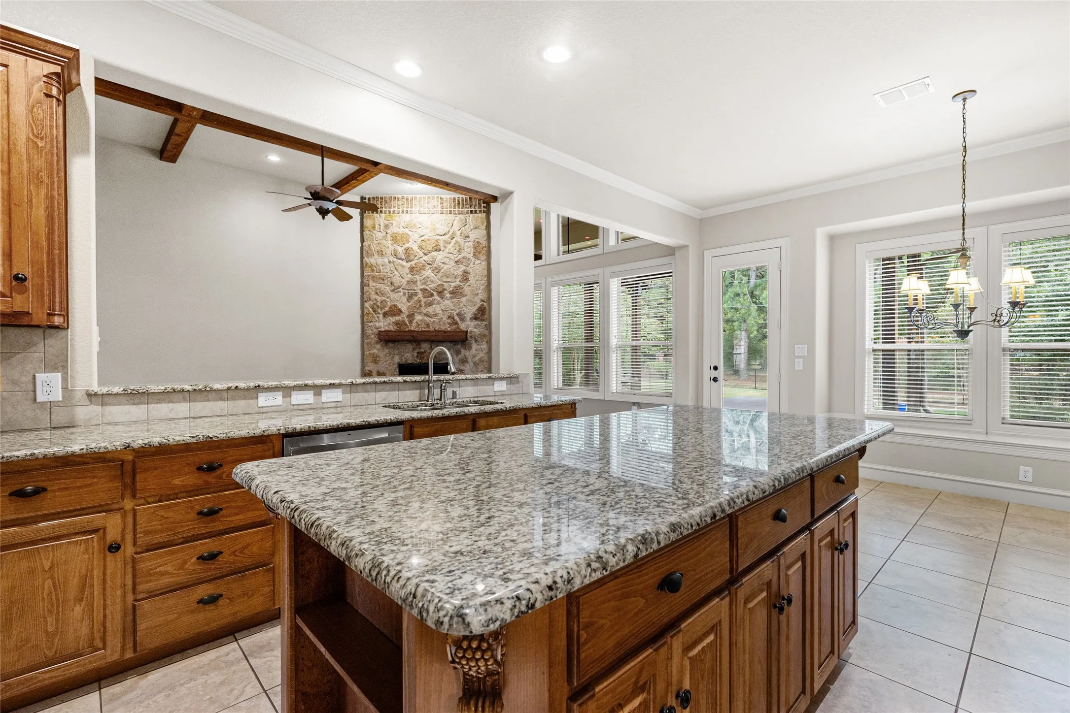 Spacious kitchen featuring granite countertops, wood cabinetry, stainless steel dishwasher, and a tile floor