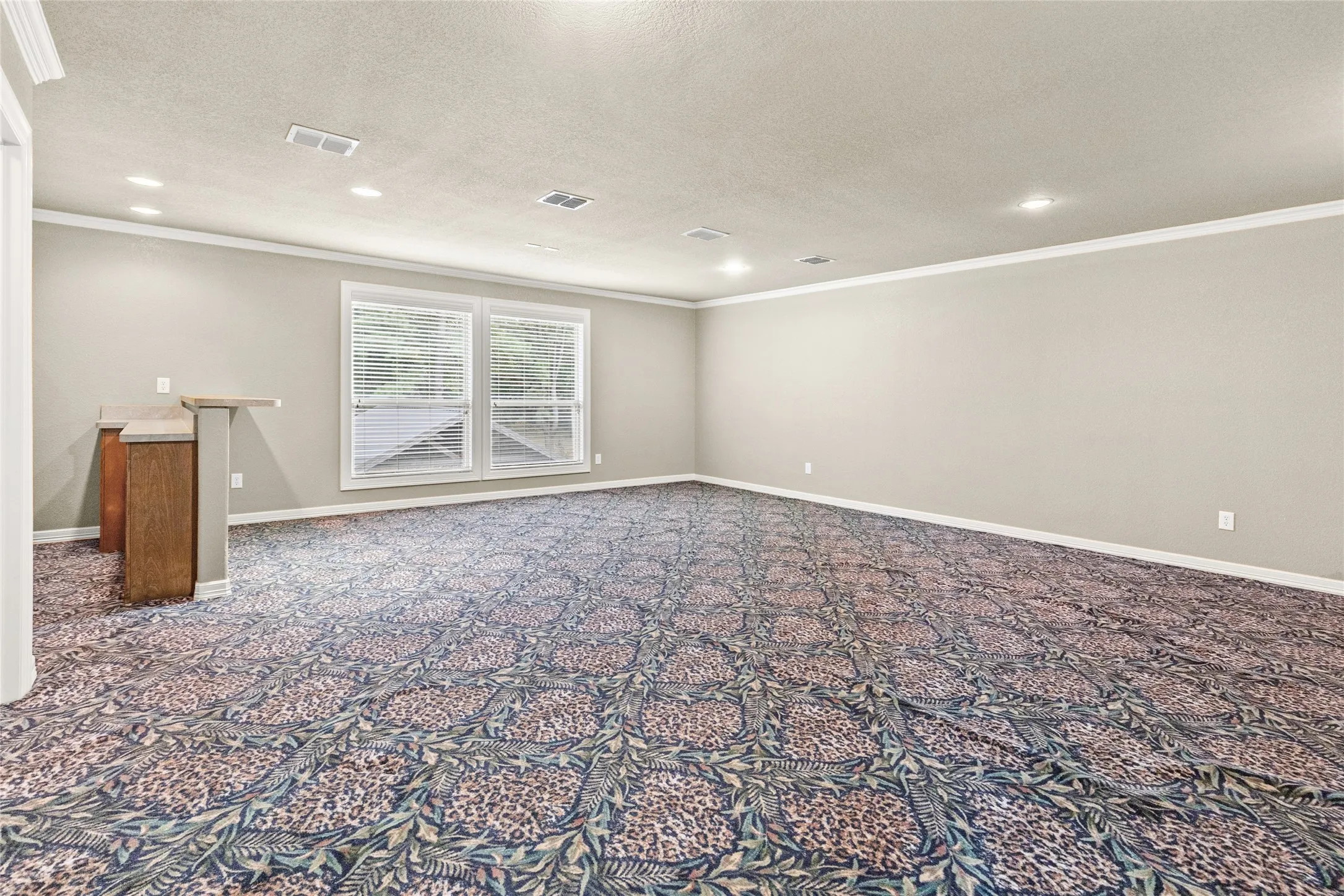 Spacious room with recessed lighting, crown molding, double windows, and a built-in bar with a wood-finish base