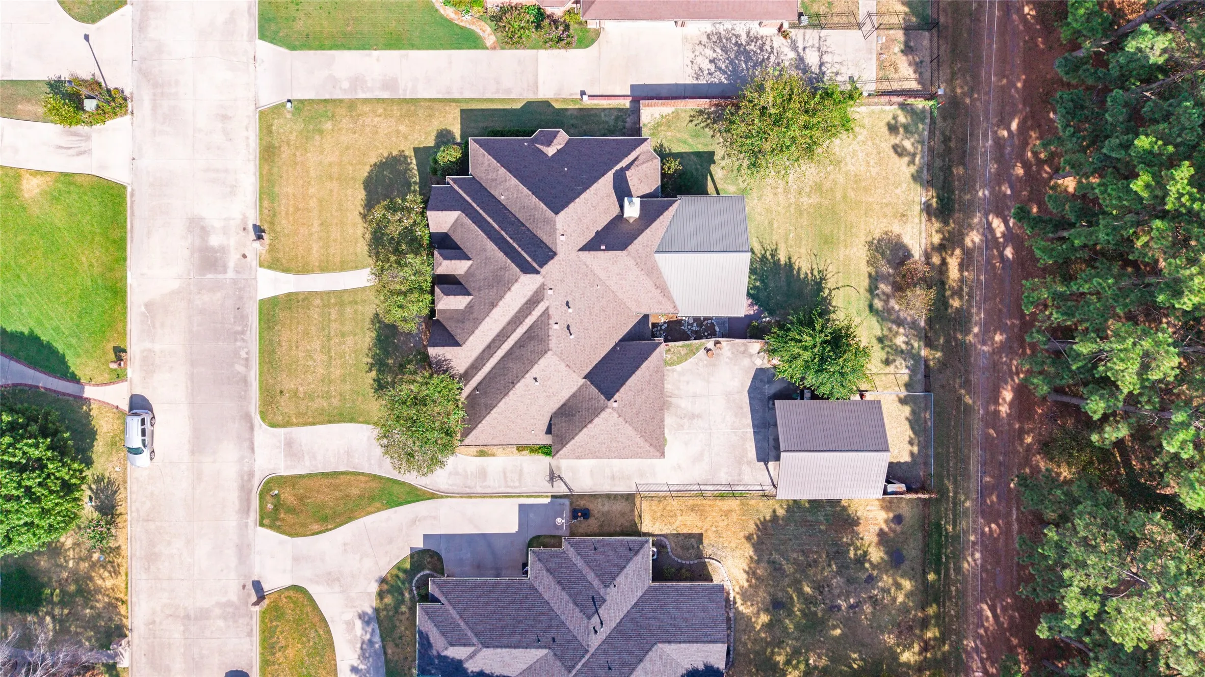 Expansive property featuring a multi-gabled roofline, concrete driveway, and a detached metal-roof structure