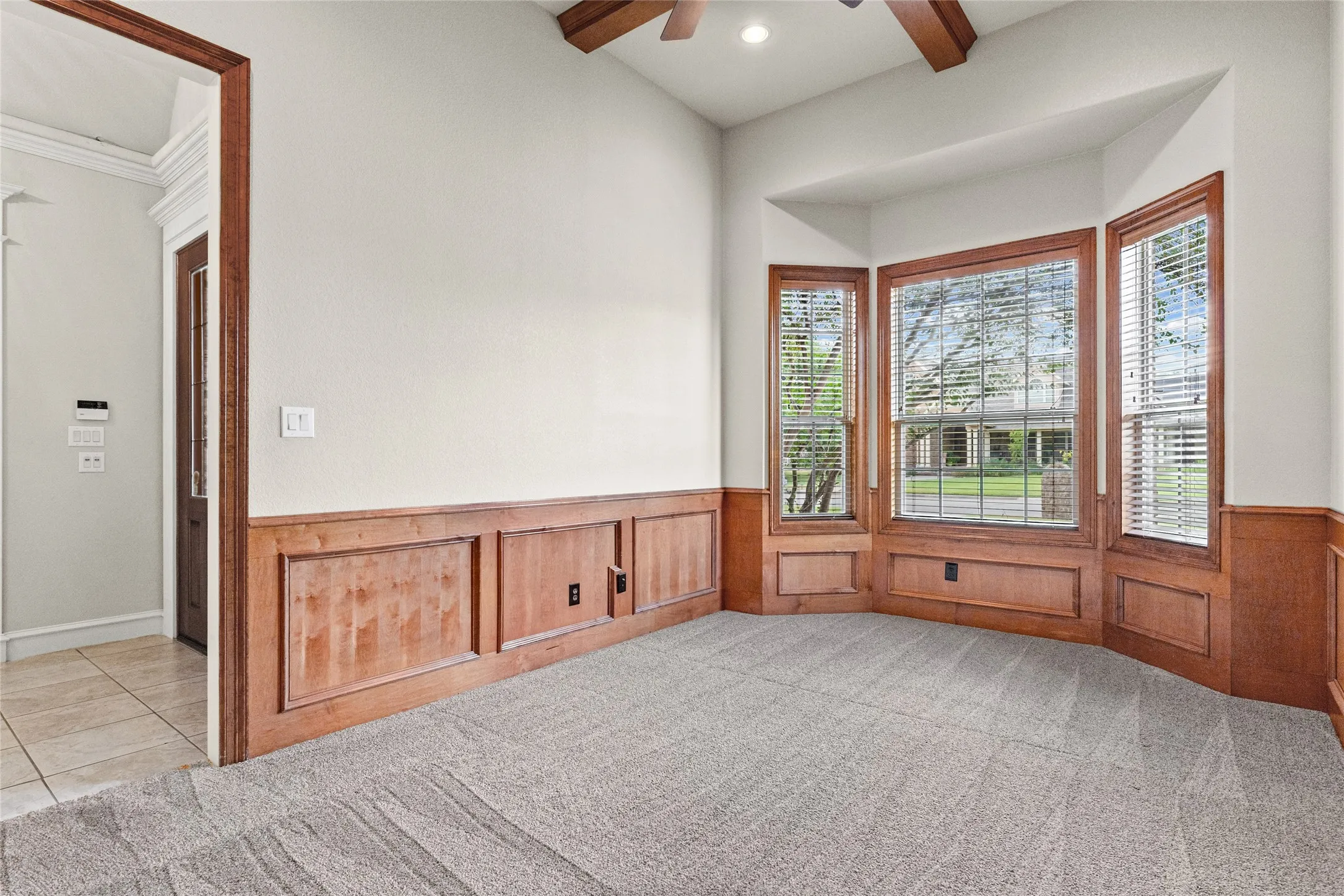 Hardwood trim and wainscoting, bay window with blinds, carpeted flooring, and a recessed light fixture