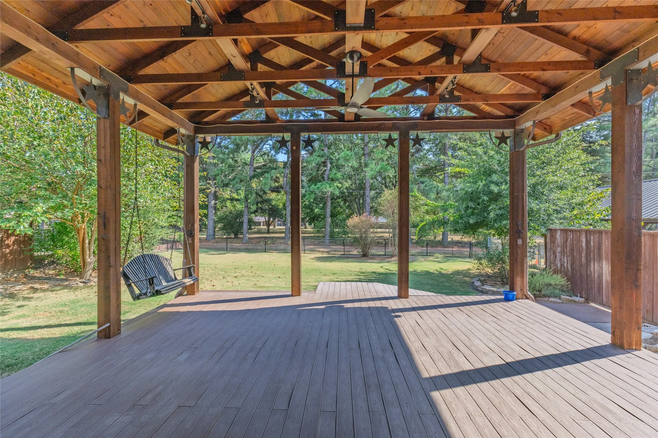 Expansive covered deck featuring a wood-finish ceiling, exposed beams, and a ceiling fan