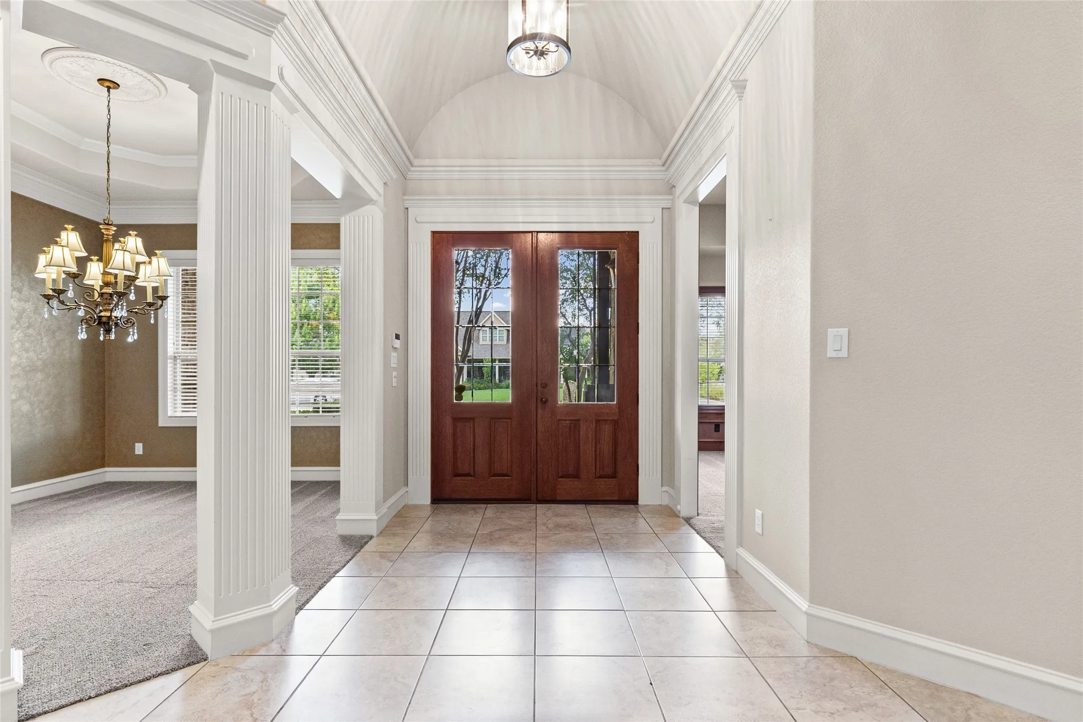 Grand entry hall featuring vaulted ceiling, tile flooring, fluted columns, and double glass-paneled entry doors
