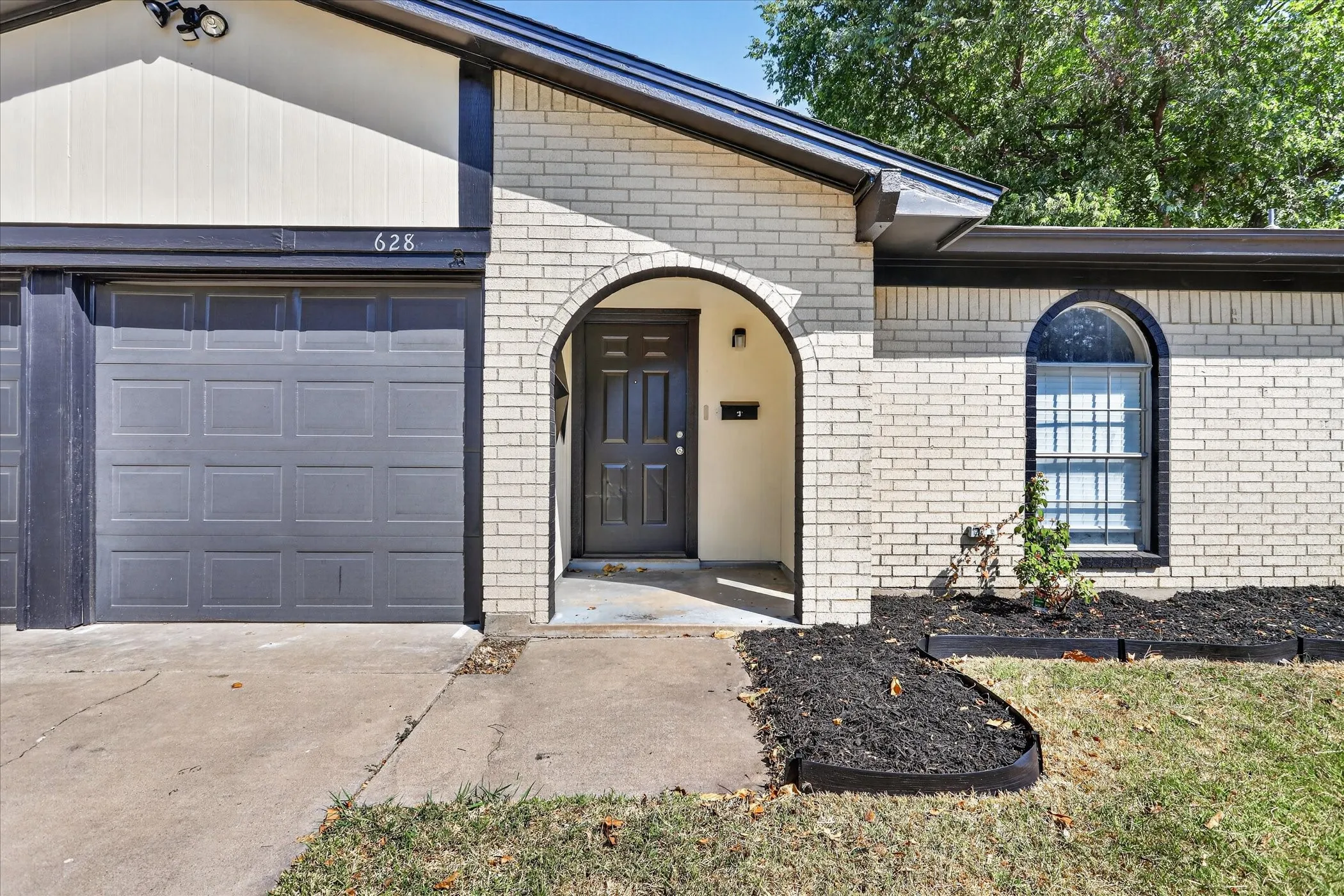 Cream brick exterior with dark trim and an arched entryway