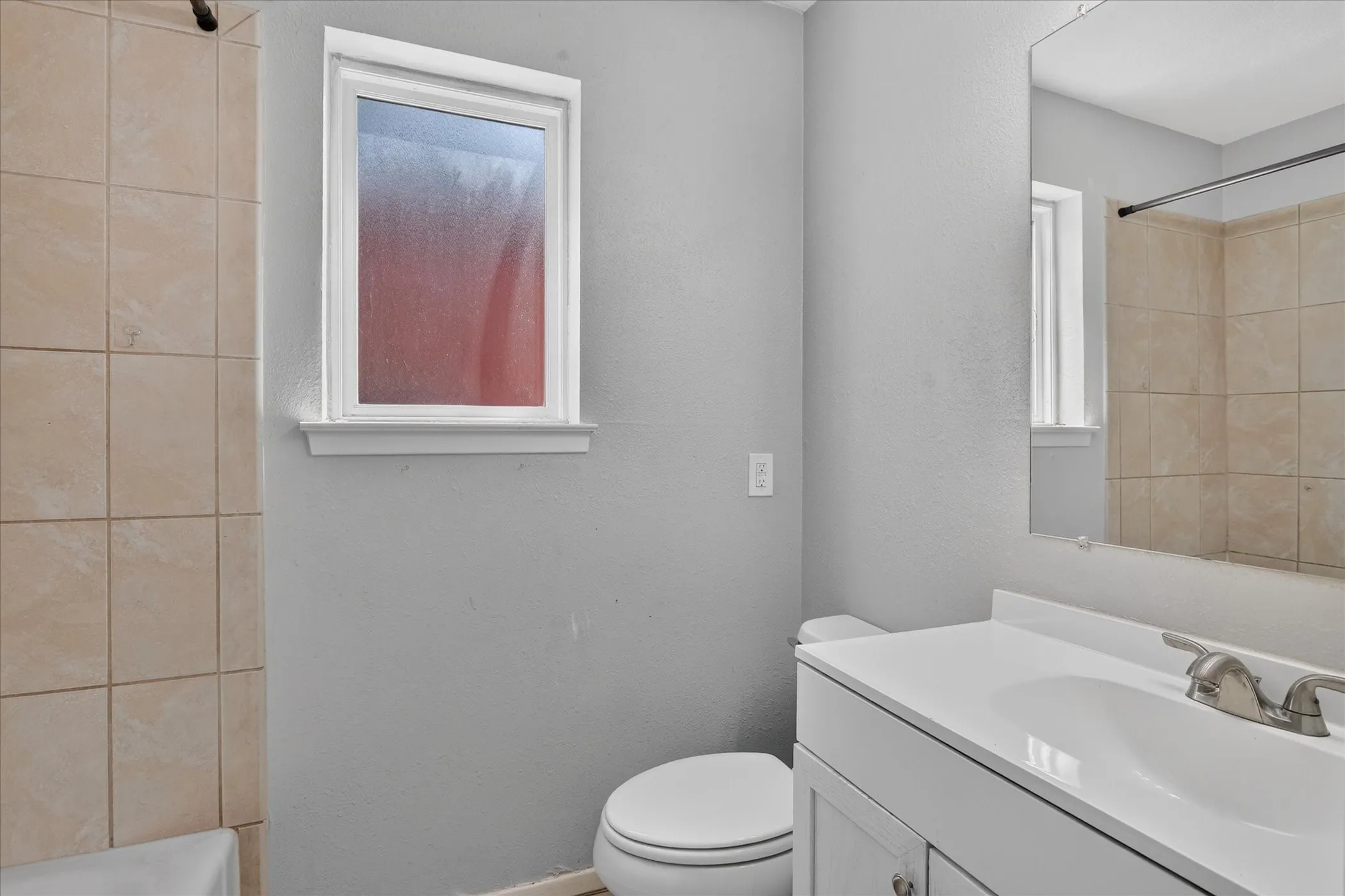 White bathtub with chrome fixtures and light-toned tile surround