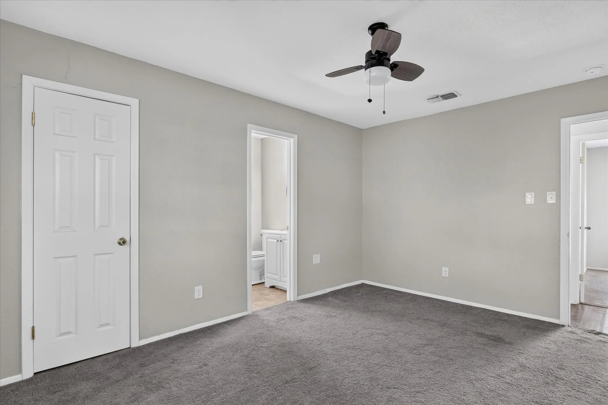 Neutral wall finishes with a ceiling fan light fixture and grey carpet flooring