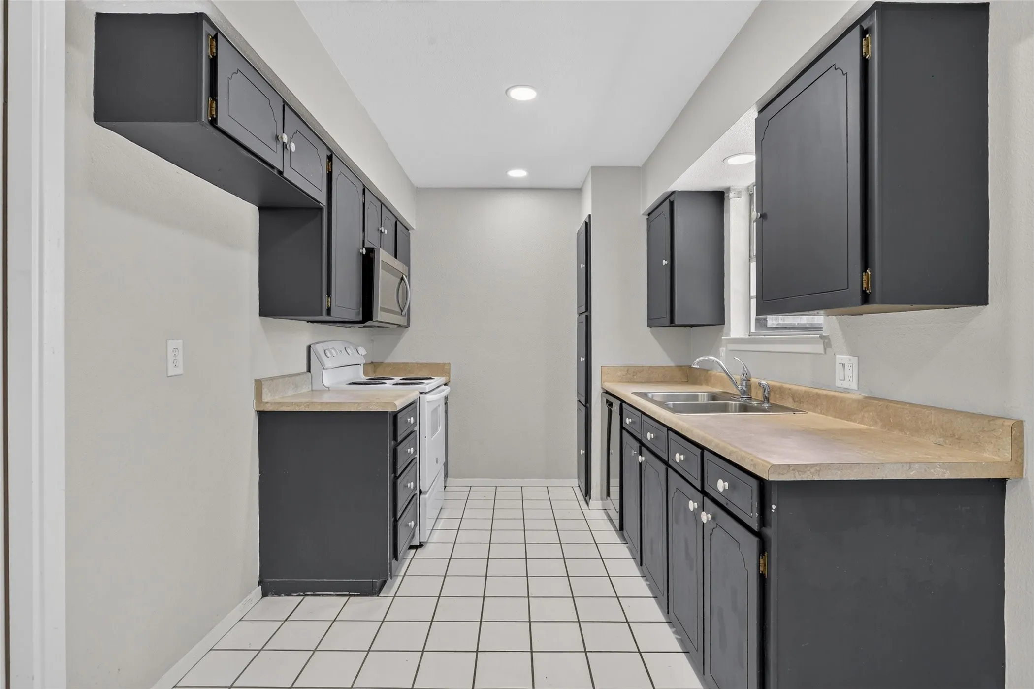 Kitchen space featuring recessed lighting, dark cabinetry, light-toned countertops, and square tile flooring
