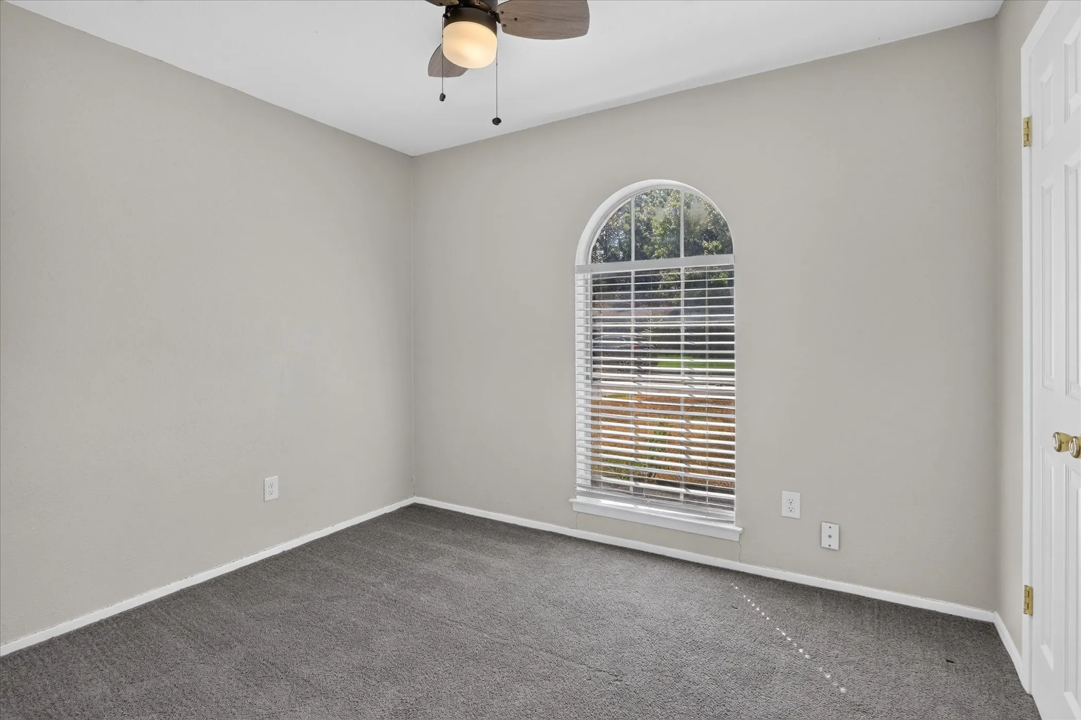 Arch-top window with blinds, ceiling fan, and grey carpeting