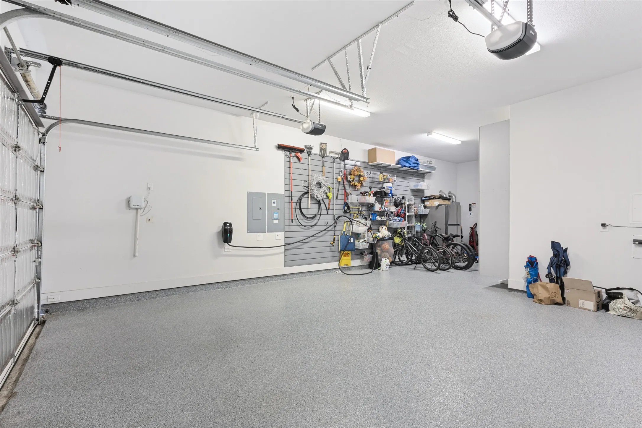 Spacious garage featuring a durable epoxy floor, integrated overhead lighting, and an electric vehicle charging station