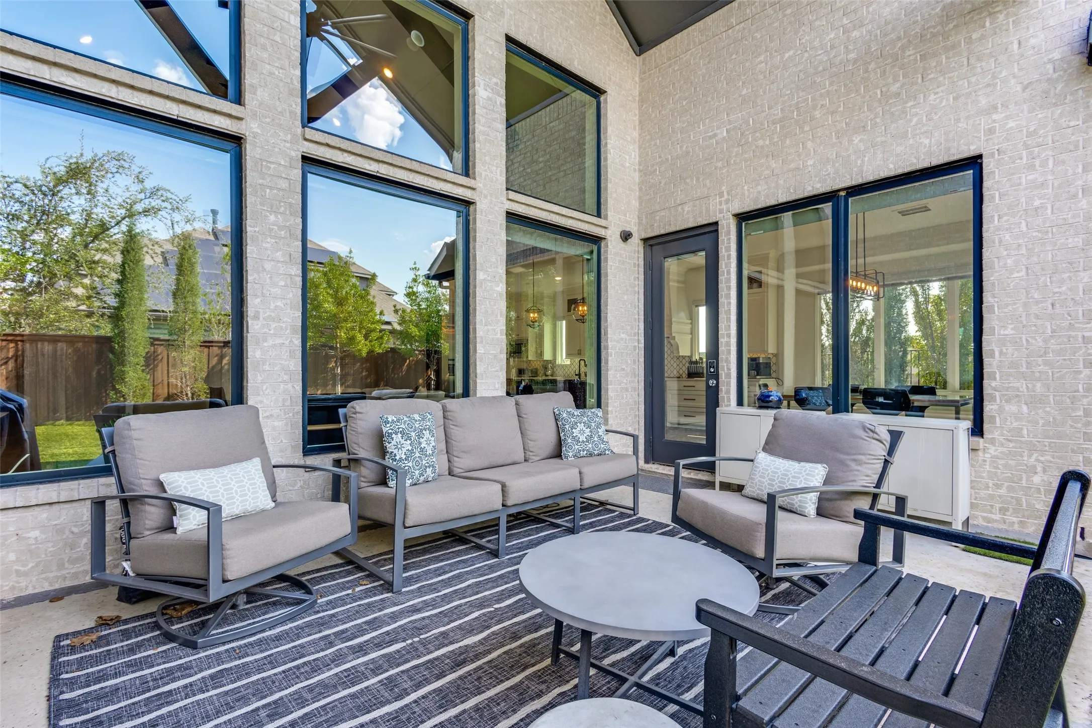 Covered patio with a high ceiling, brick exterior, and expansive windows