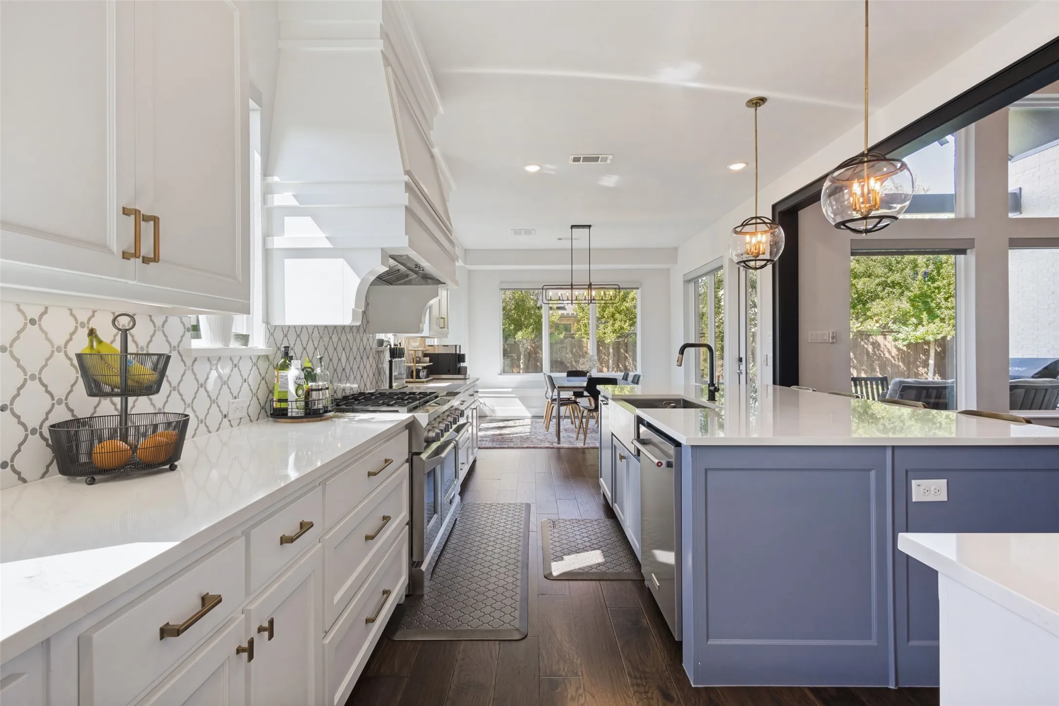 Gourmet kitchen with white perimeter cabinetry, a large range, a custom range hood, a contrasting blue island, and wood-finish flooring
